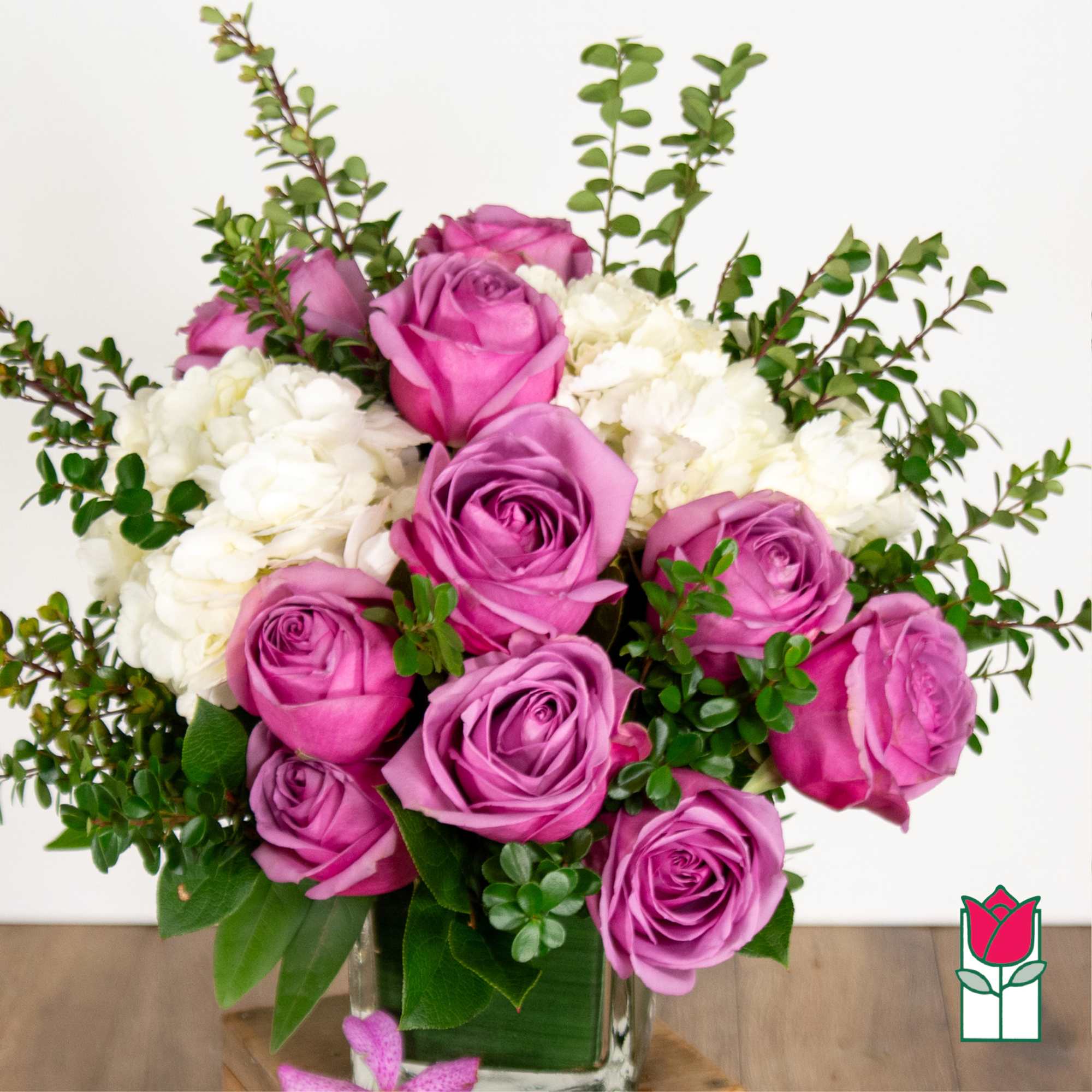Pink and lavender roses with white blooms in a clear glass vase