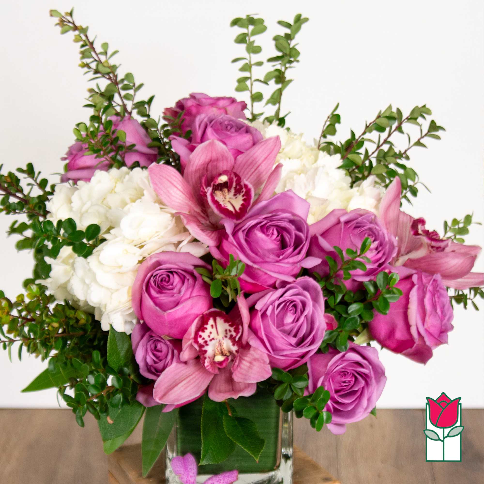 Pink roses and orchids arranged in a clear glass vase