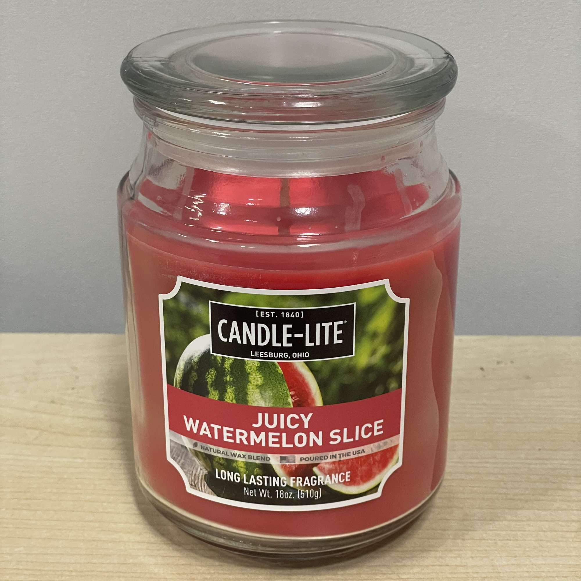 Red watermelon-scented candle in a glass jar