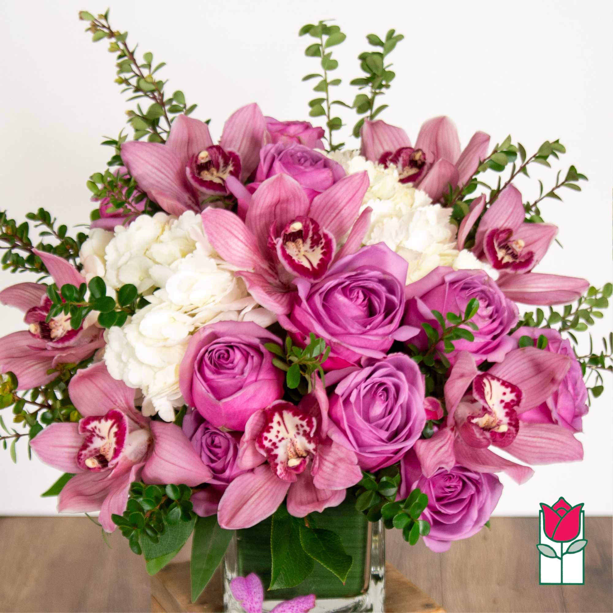 Pink orchids and roses arranged in a clear glass vase