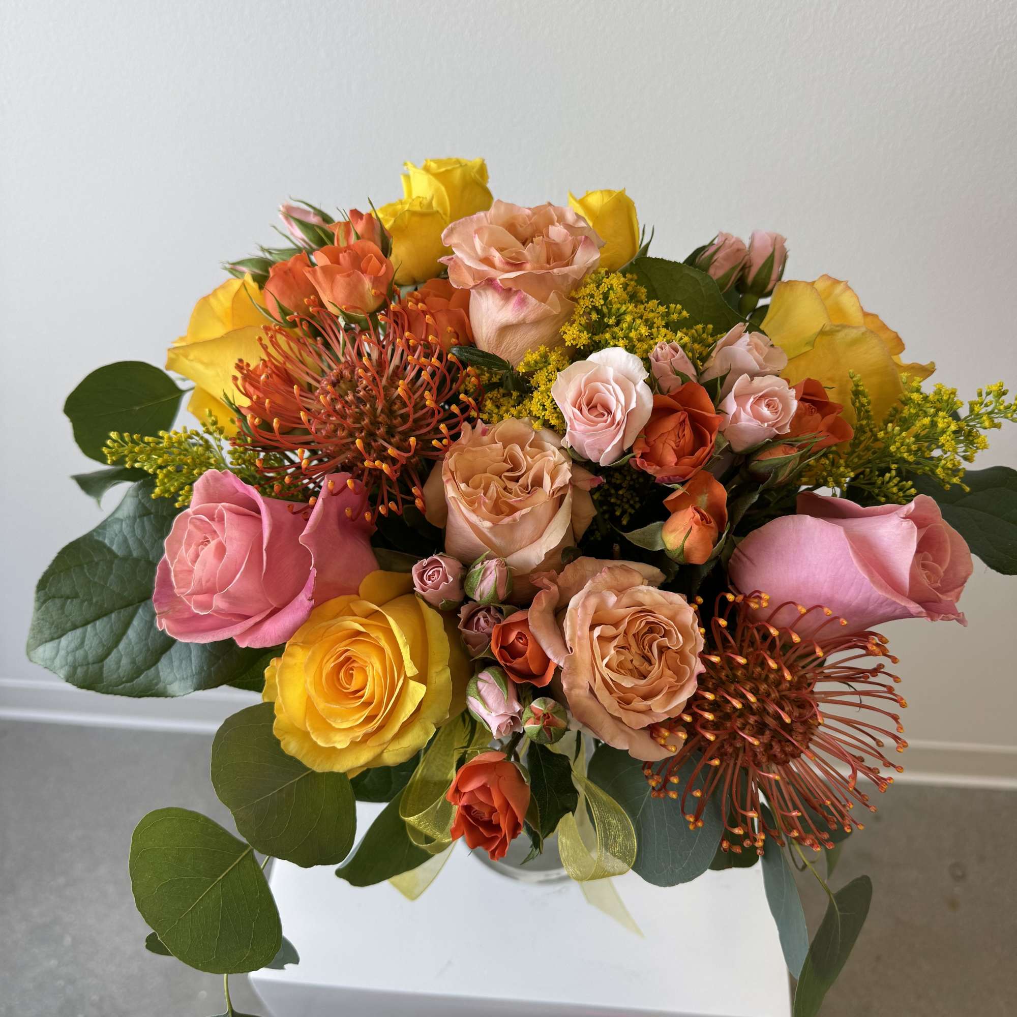 Mixed bouquet of pink, yellow, and peach roses with orange accent blooms