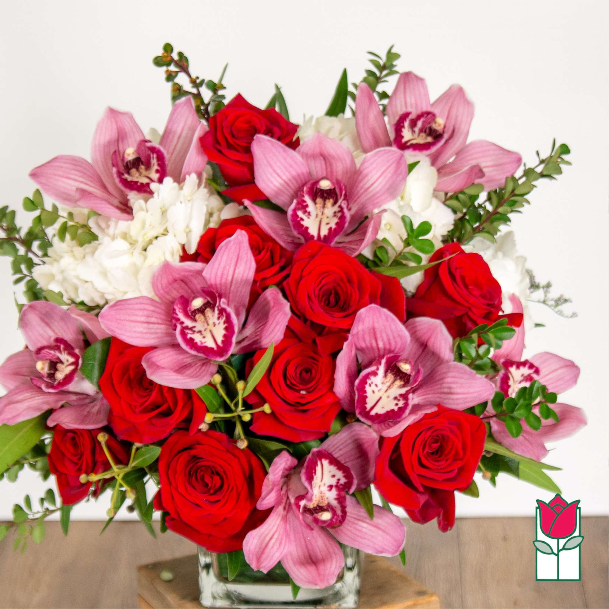 Bouquet of red roses and pink orchids in a glass vase