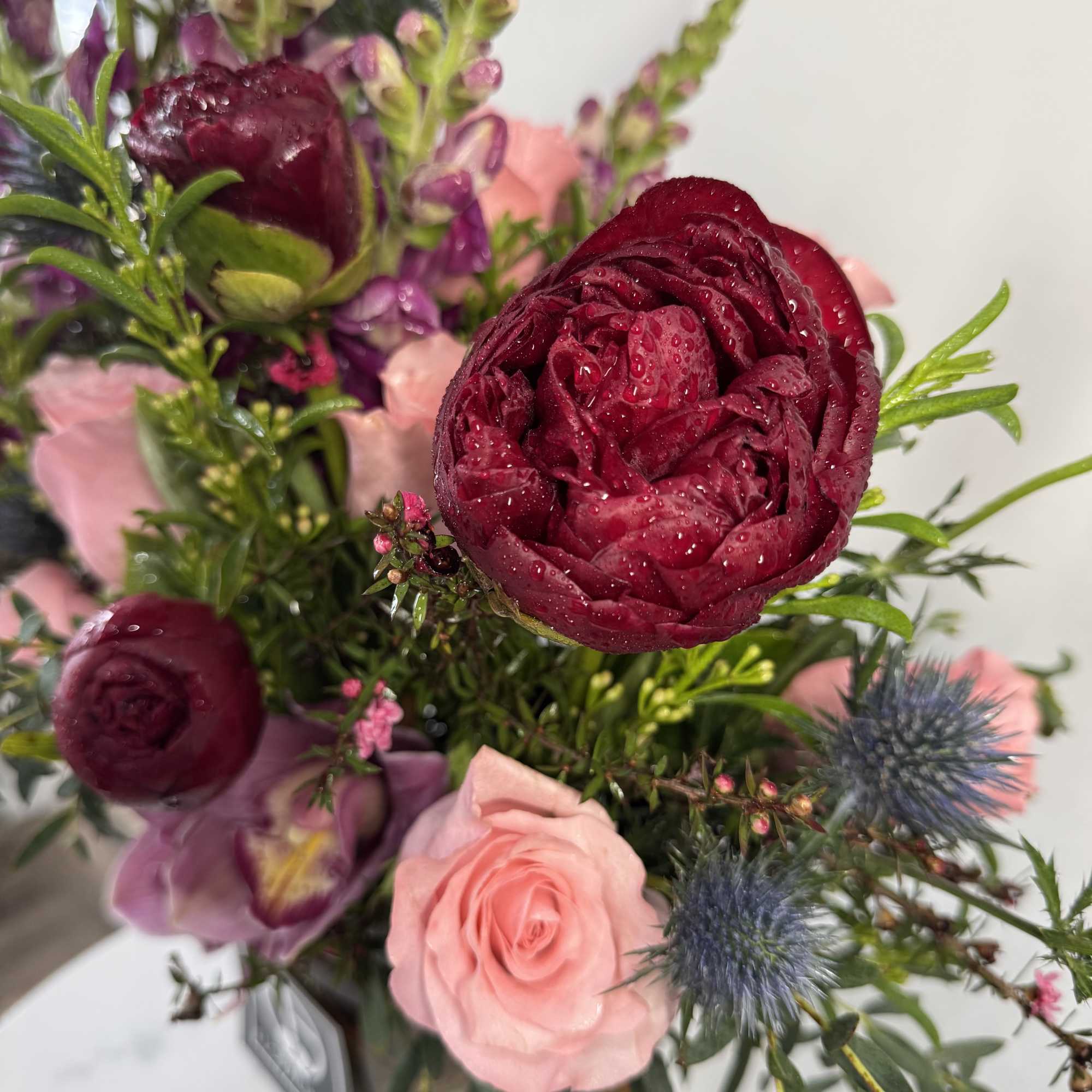 Bouquet of burgundy and pink flowers with blue thistle accents