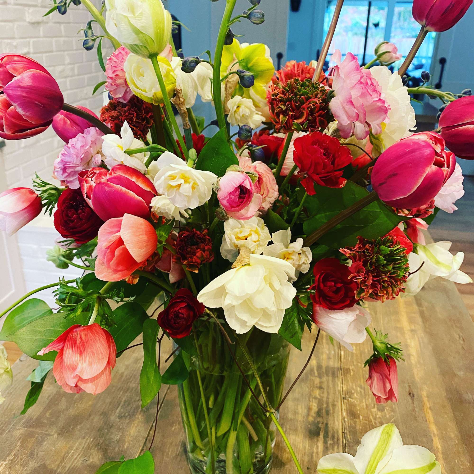 Mixed bouquet of pink, red, and white tulips in a clear glass vase