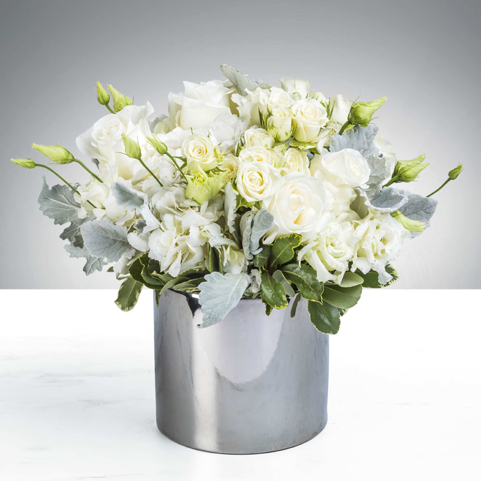 White roses and lisianthus in a silver vase