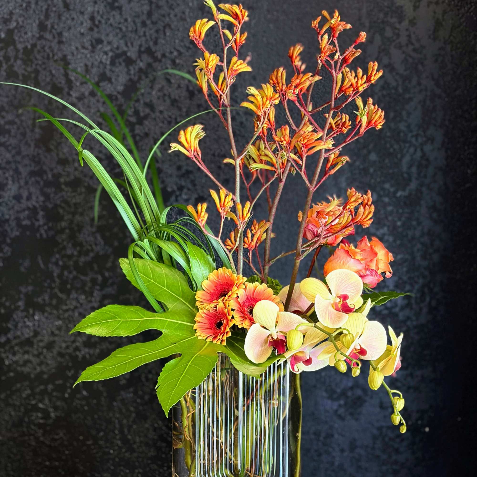 Warm, tropical energy bursts from this contemporary flower arrangement. The vertical silhouette