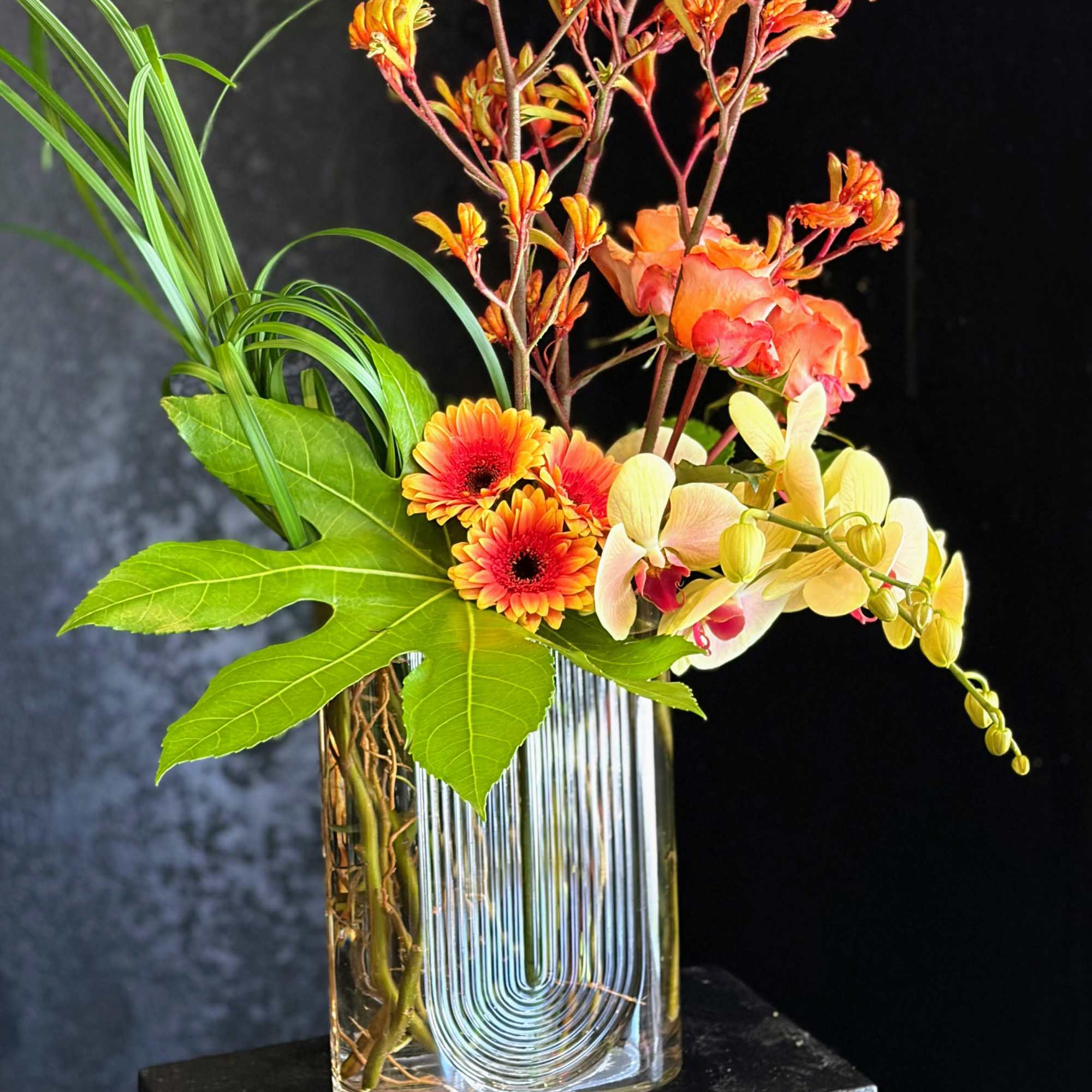 Warm, tropical energy bursts from this contemporary flower arrangement. The vertical silhouette