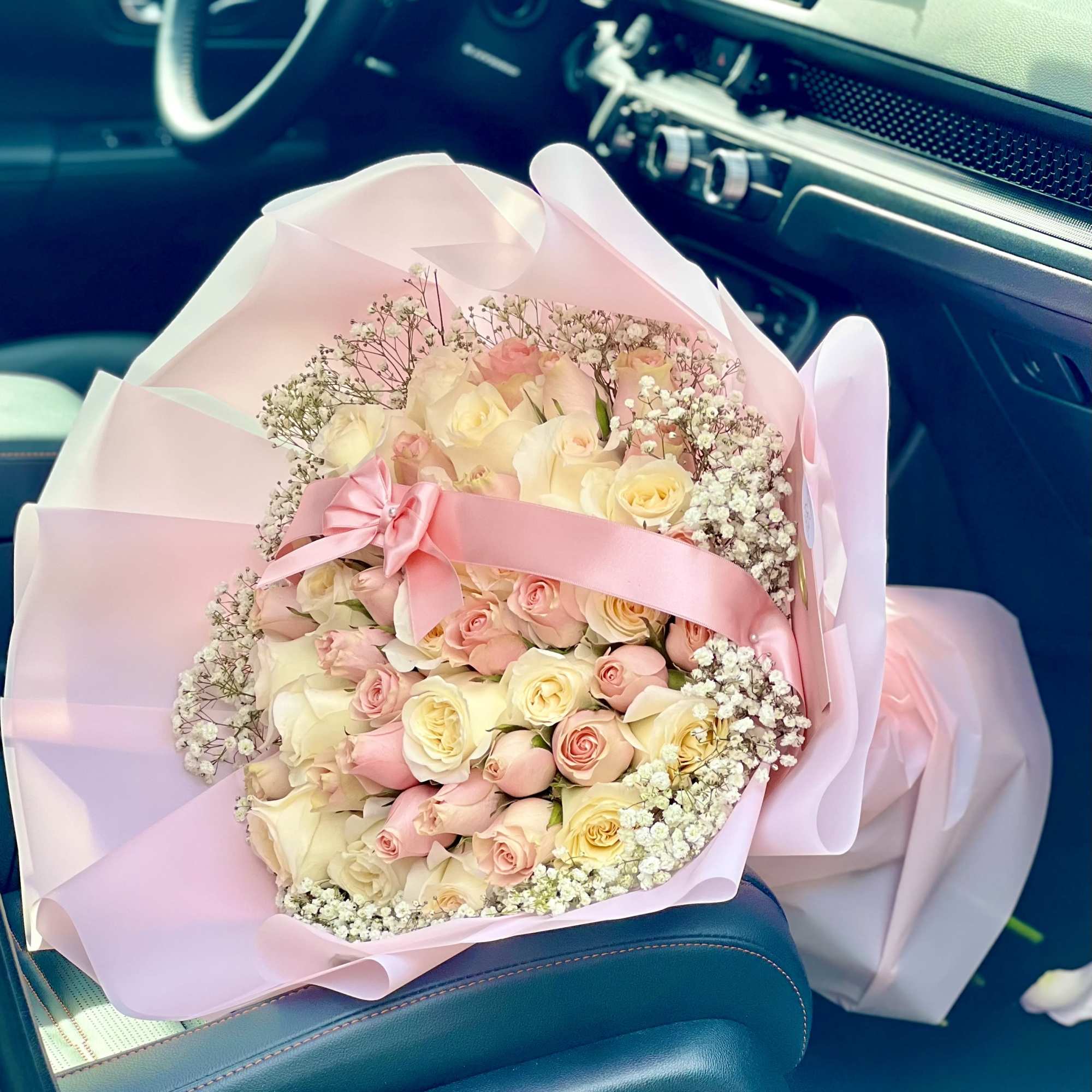 Bouquet of pale pink and cream roses wrapped in pink paper