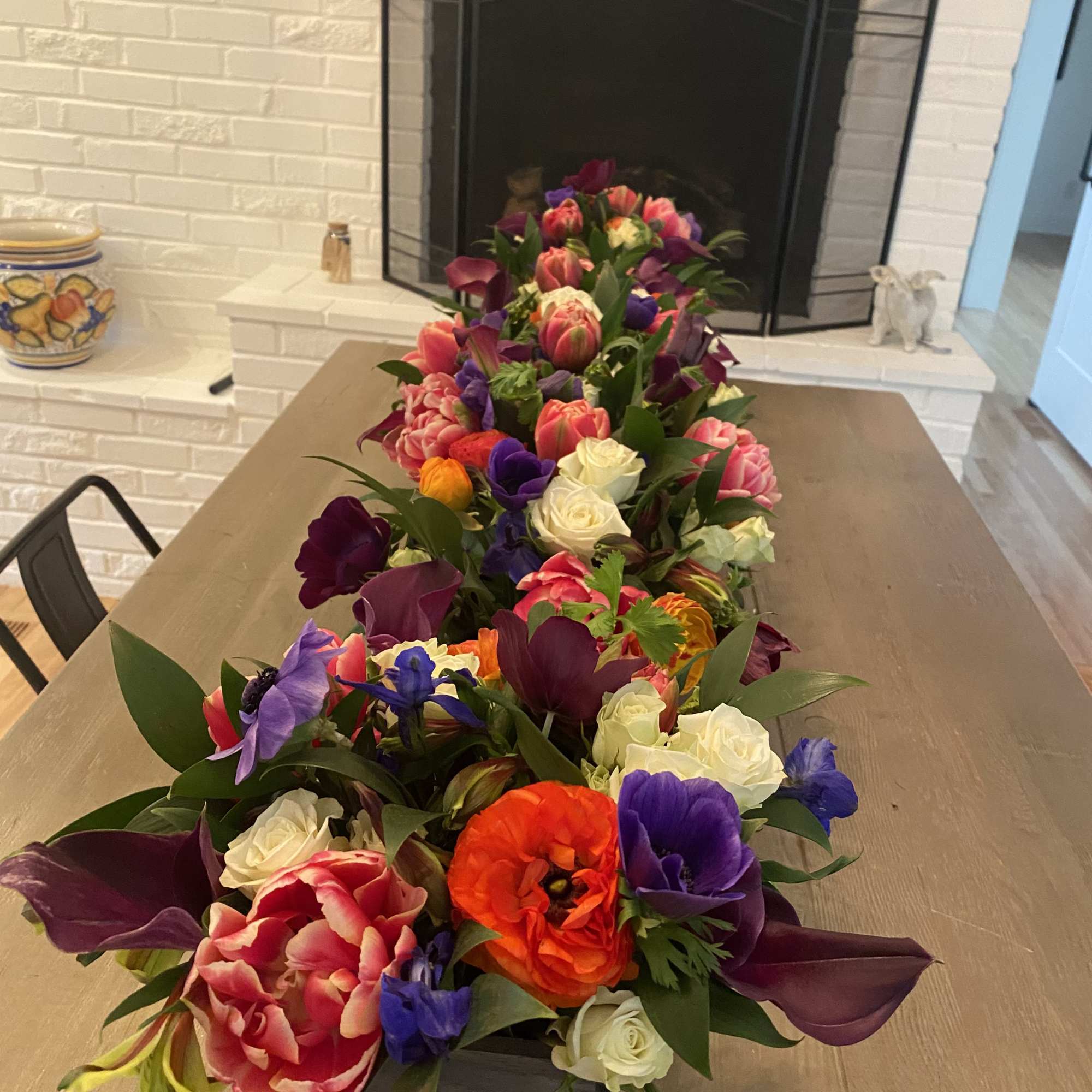 Long floral arrangement with multicolored blooms in a black container