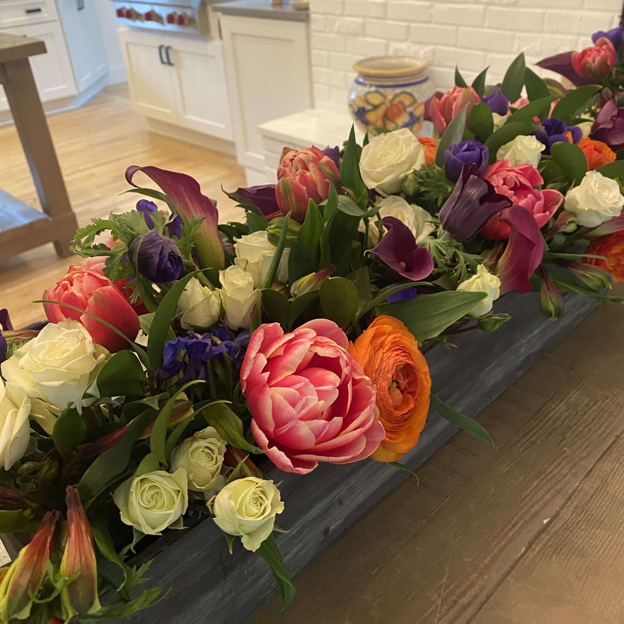 Long floral arrangement with pink, white, purple, and orange blooms in a low container
