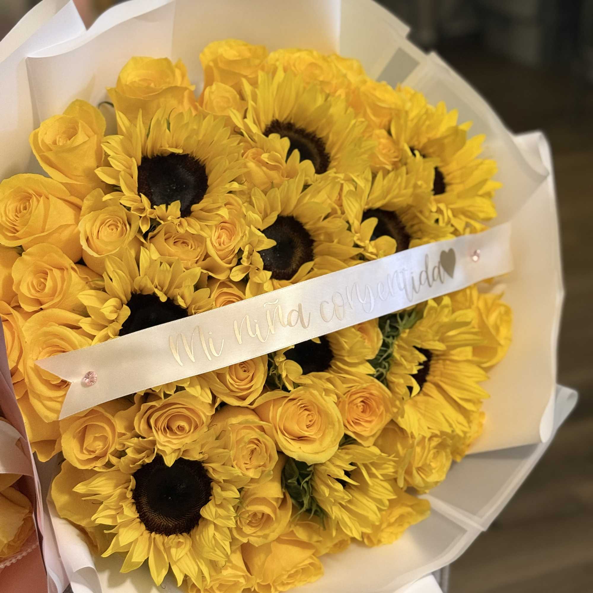 Bouquet of yellow roses and sunflowers wrapped in white paper