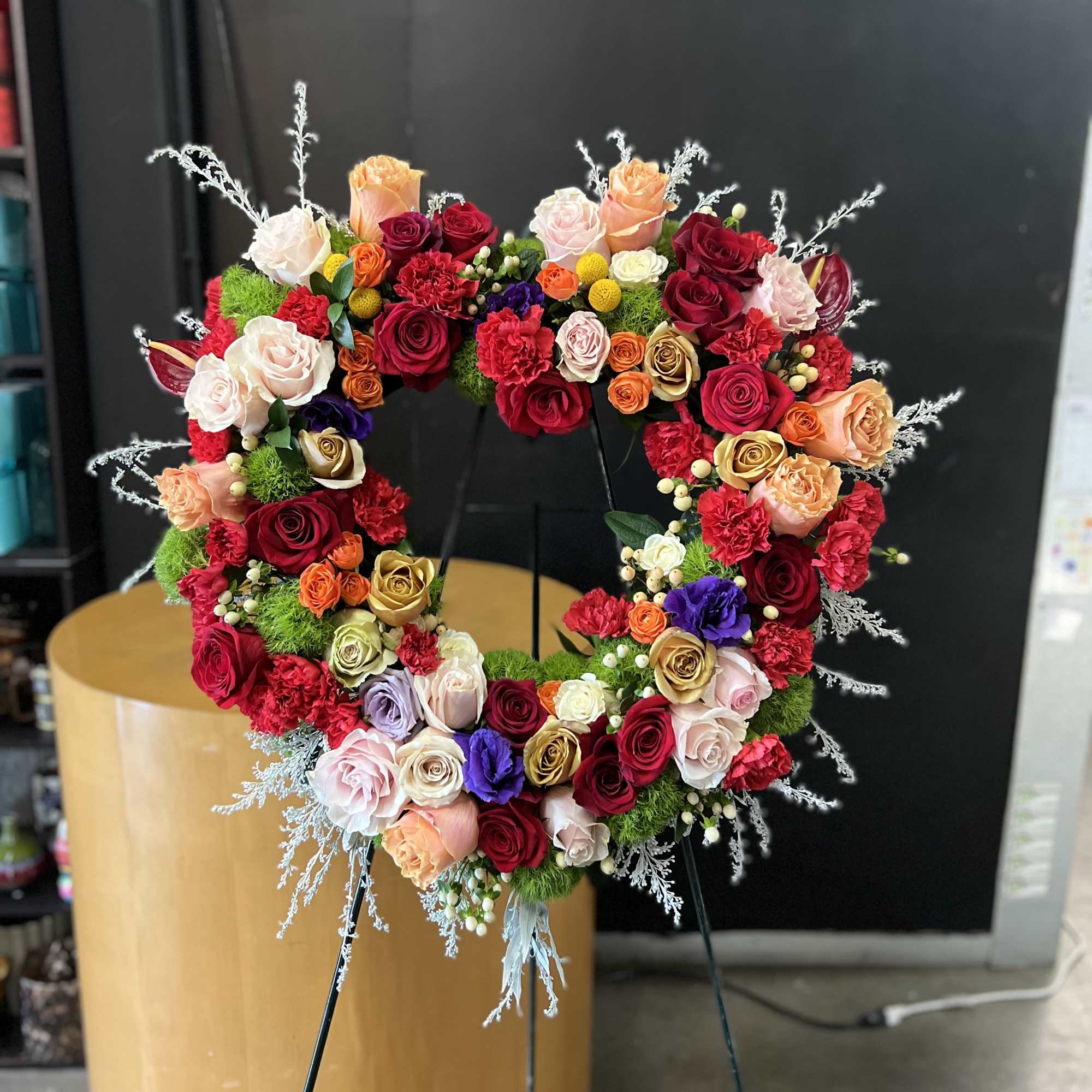 A lush heart-shaped wreath of roses and carnations creates an immediate, emotive