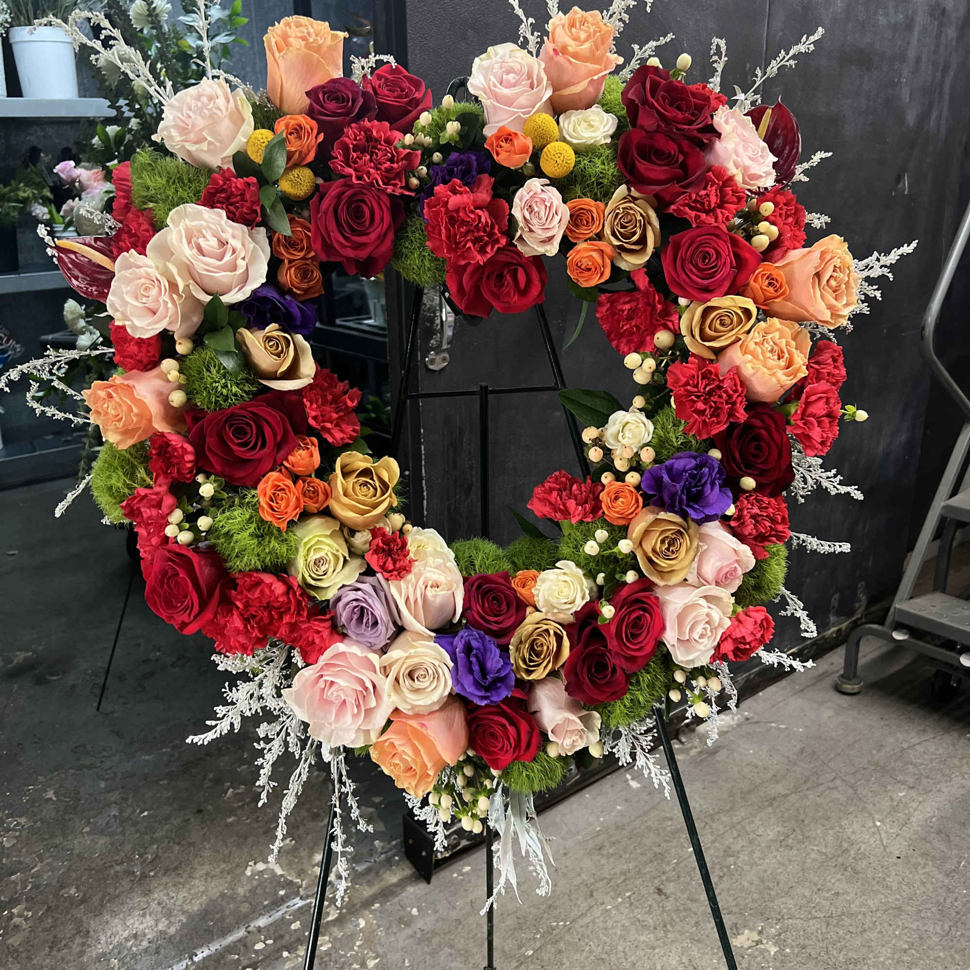 A lush heart-shaped wreath of roses and carnations creates an immediate, emotive
