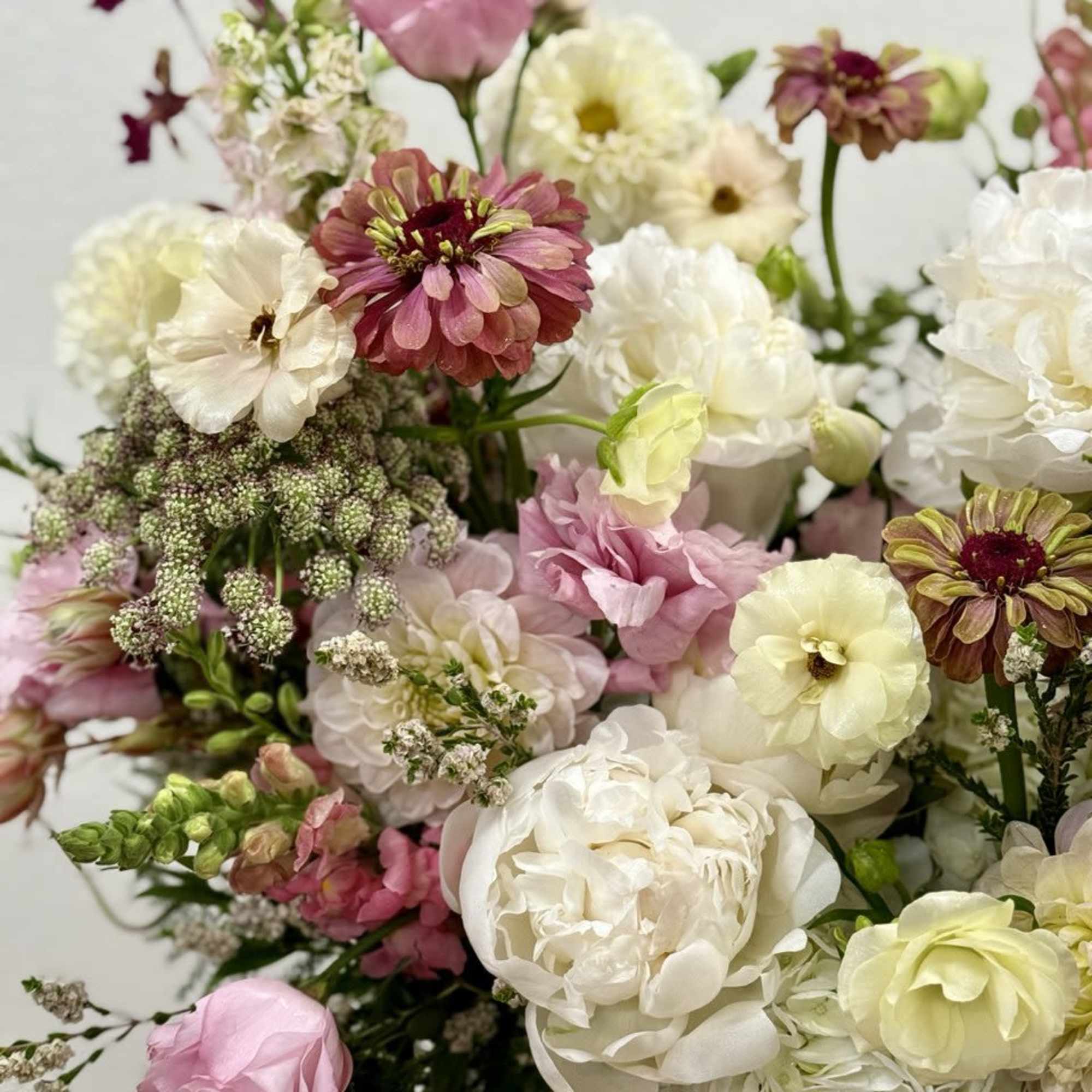 Lush garden-style arrangement of white and blush flowers with soft yellow and mauve accents