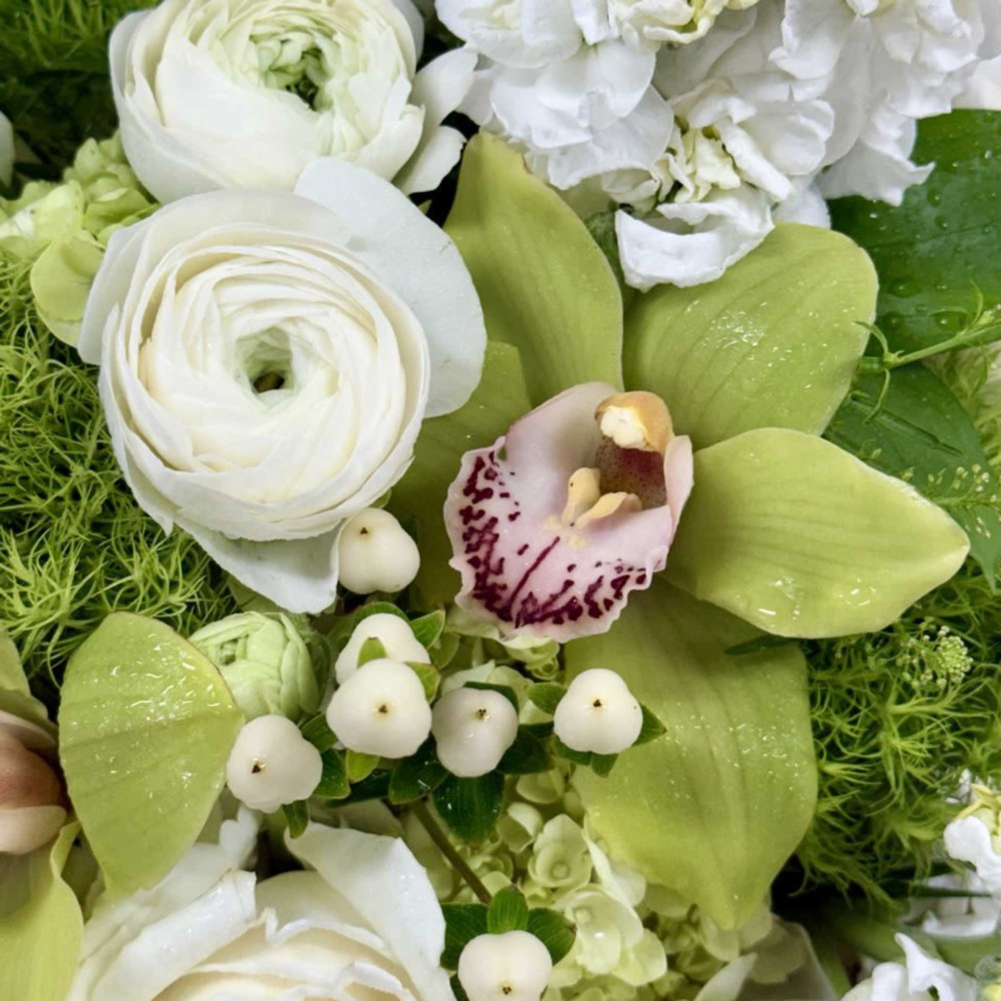 White flowers with pale green orchids and berries in a close-up bouquet
