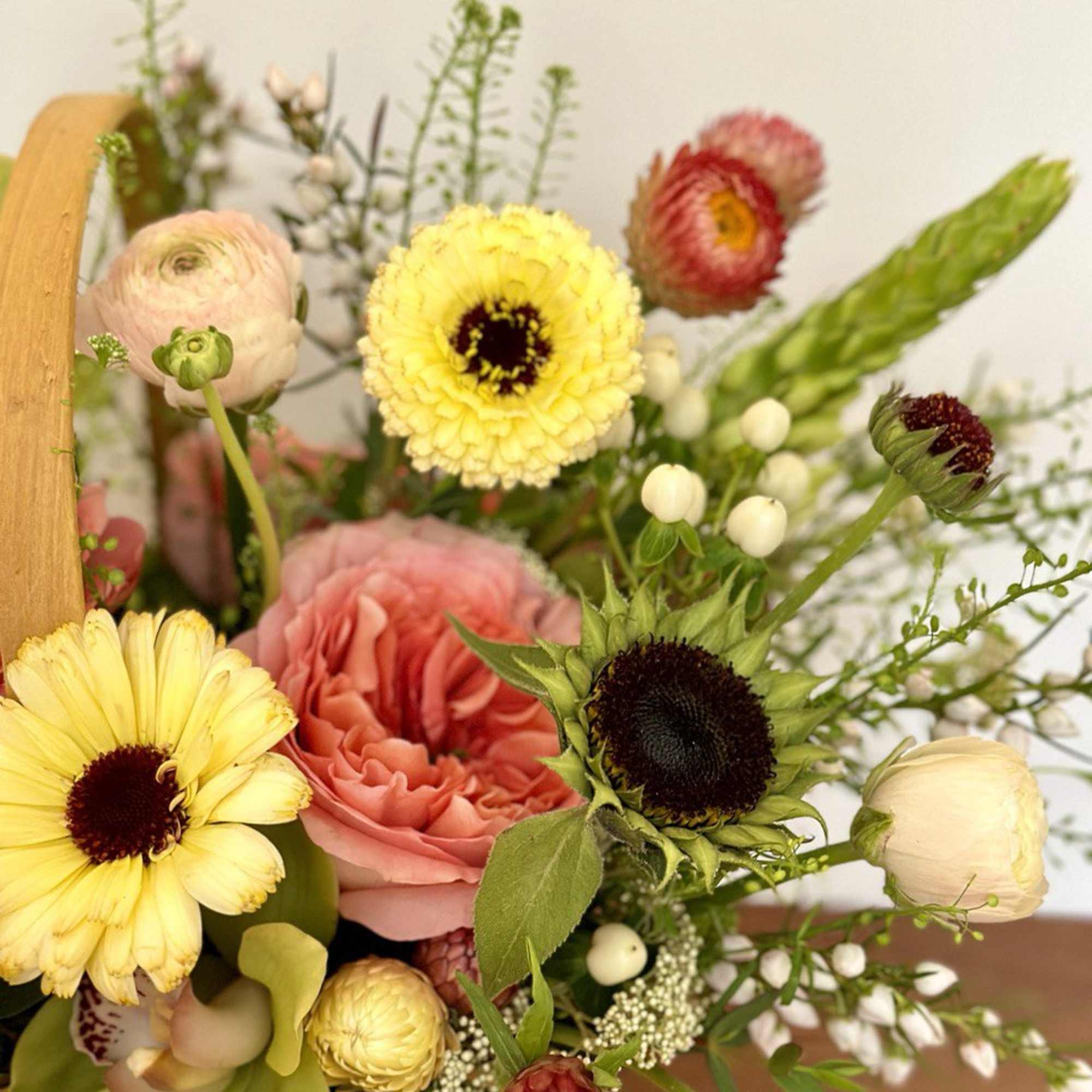 Mixed bouquet with yellow and pink blooms in a wooden basket