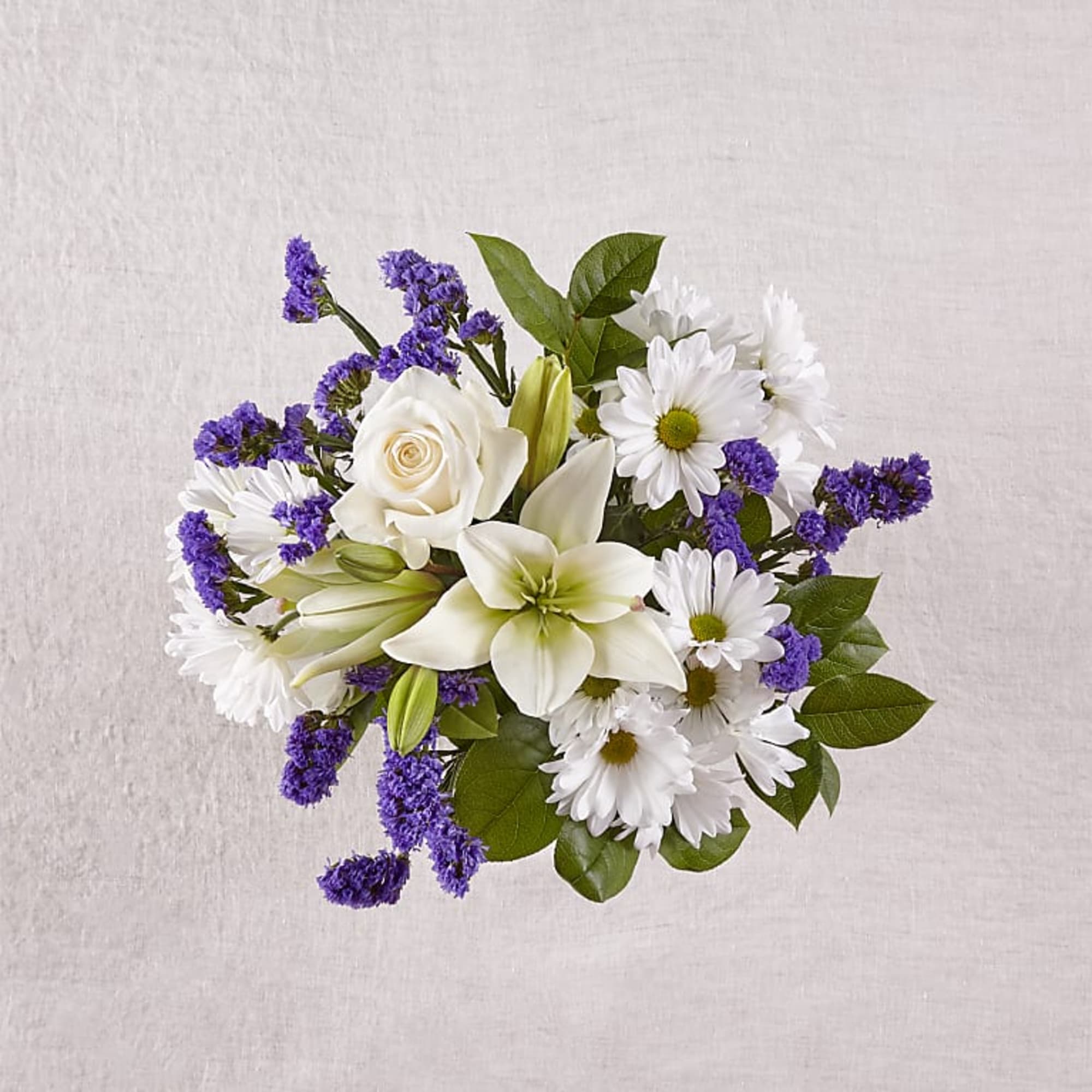 White lilies, roses, and daisies with purple filler flowers