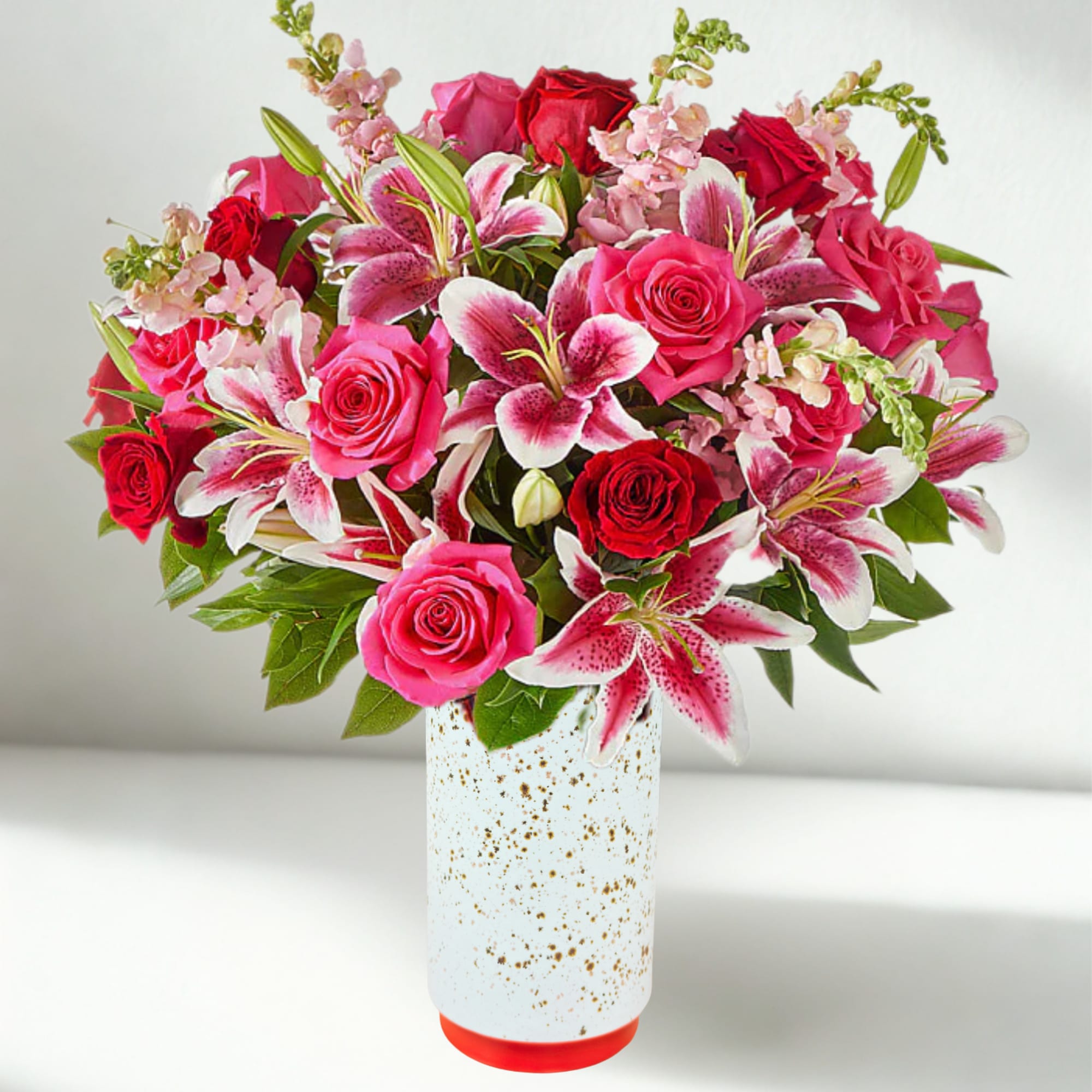 Pink and red roses with lilies in a white vase
