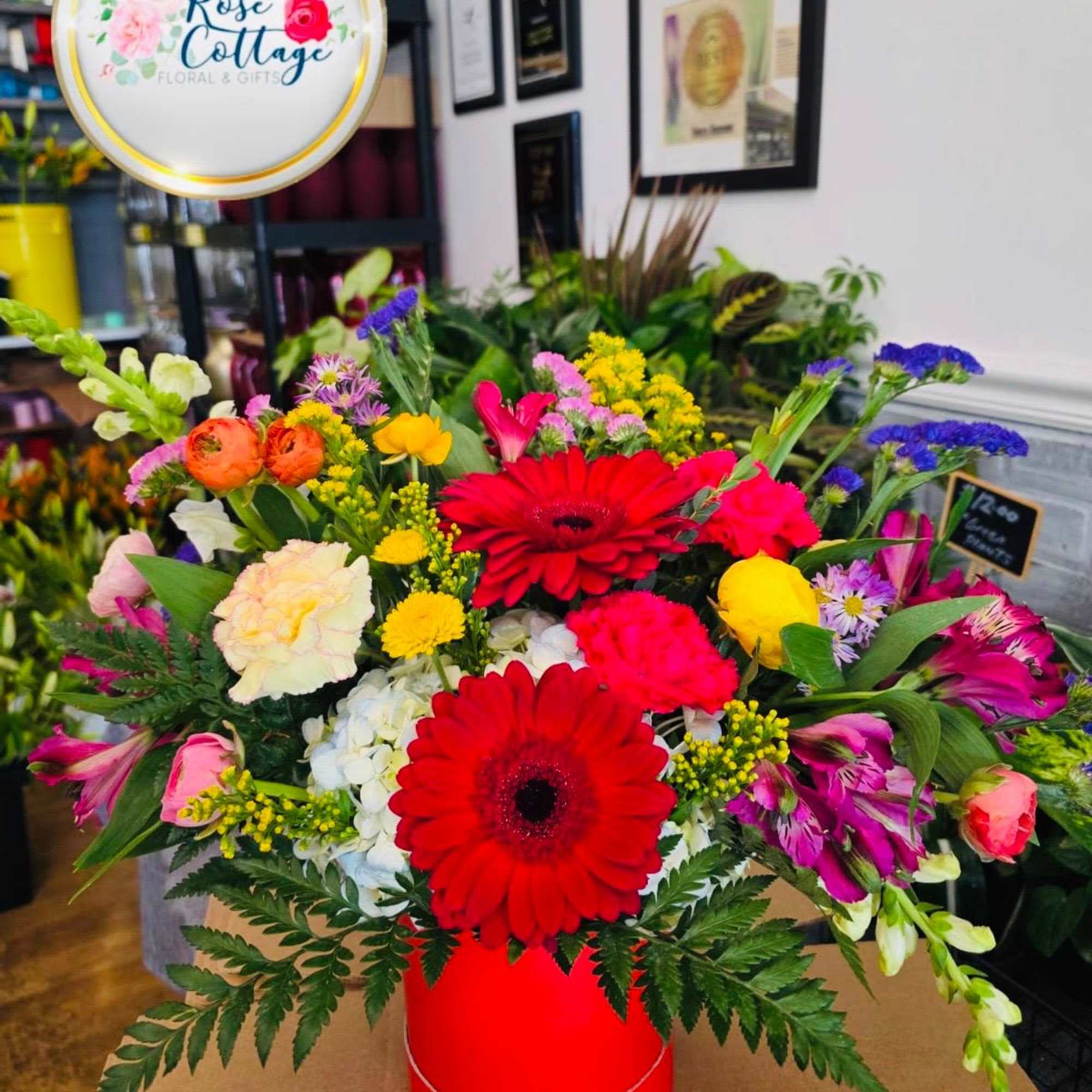 Mixed bouquet with red gerbera daisies in a red container