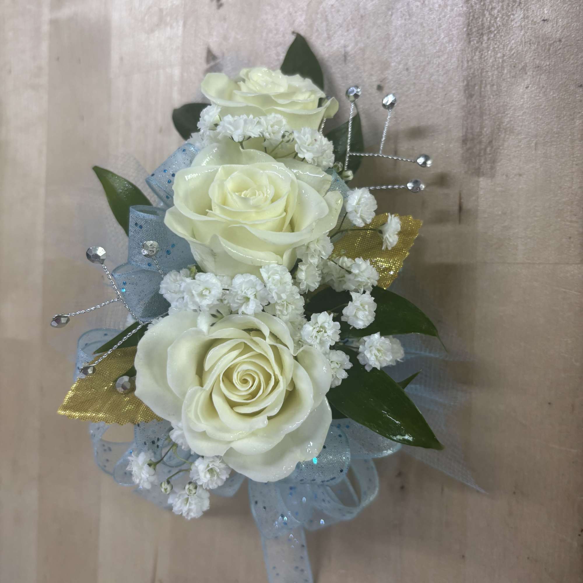 This classic wrist corsage features soft white roses, delicate baby&rsquo;s breath, and