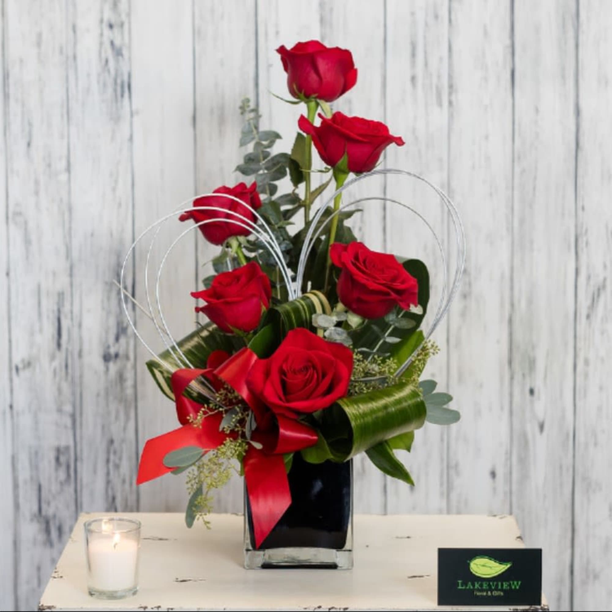Red roses arranged in a black vase with a red ribbon