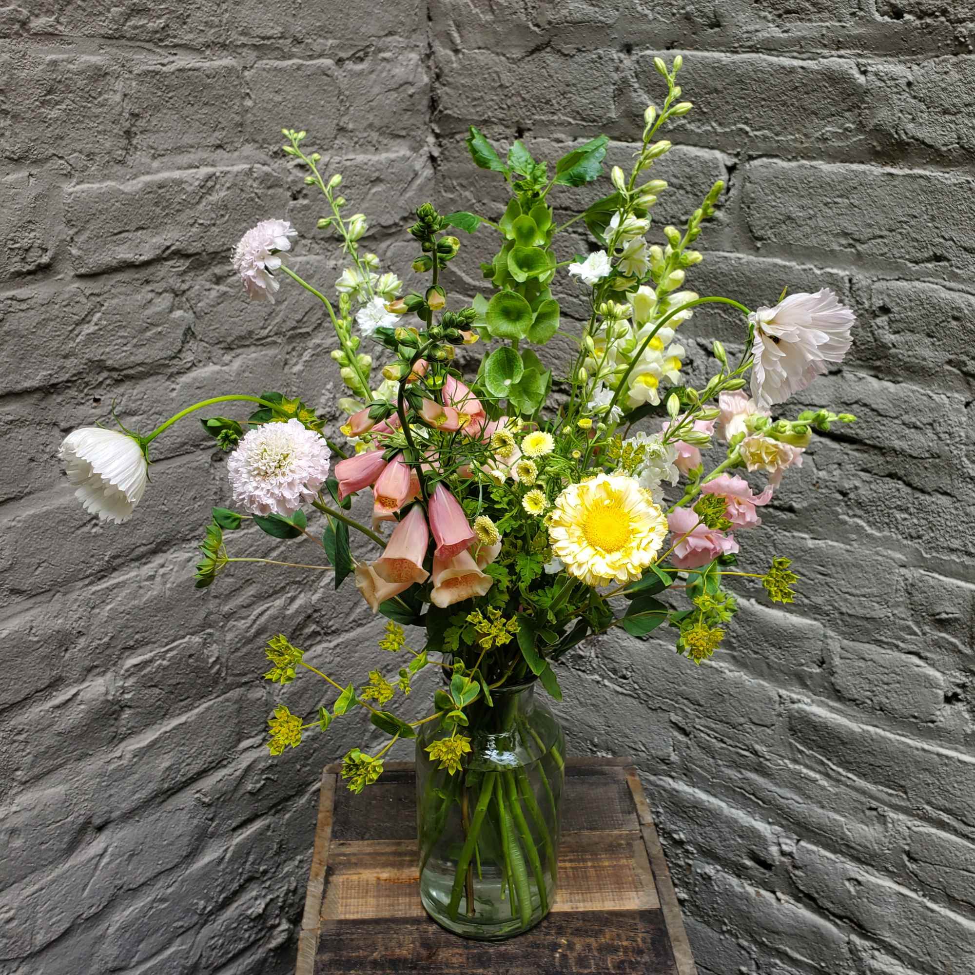 Mixed bouquet in a clear glass vase with pink, white, and yellow blooms