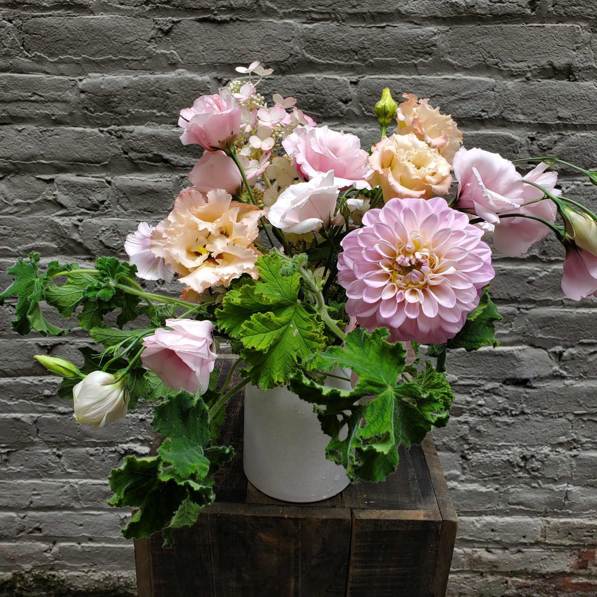 Pink and peach flowers arranged in a white vase