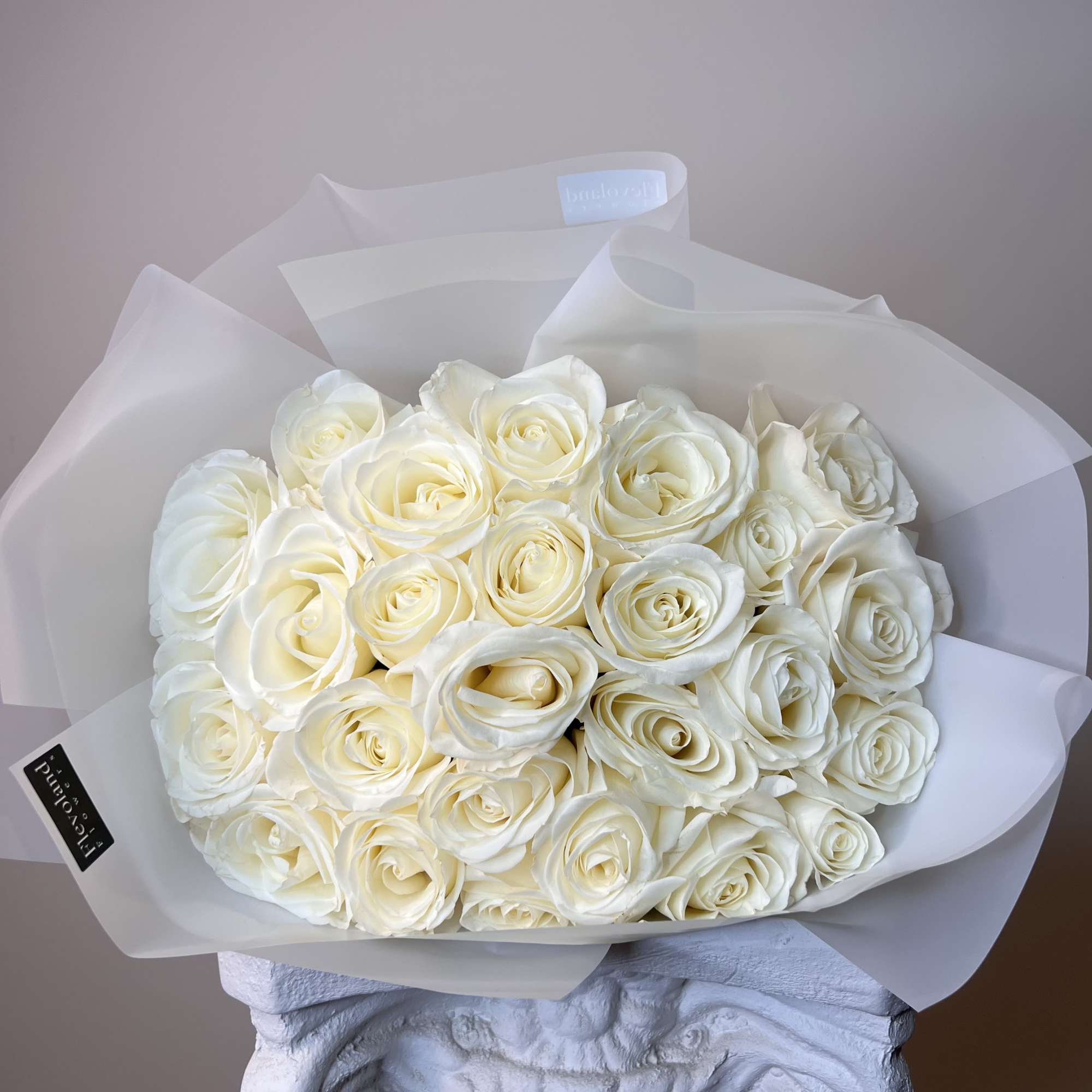 Bouquet of white roses wrapped in translucent paper