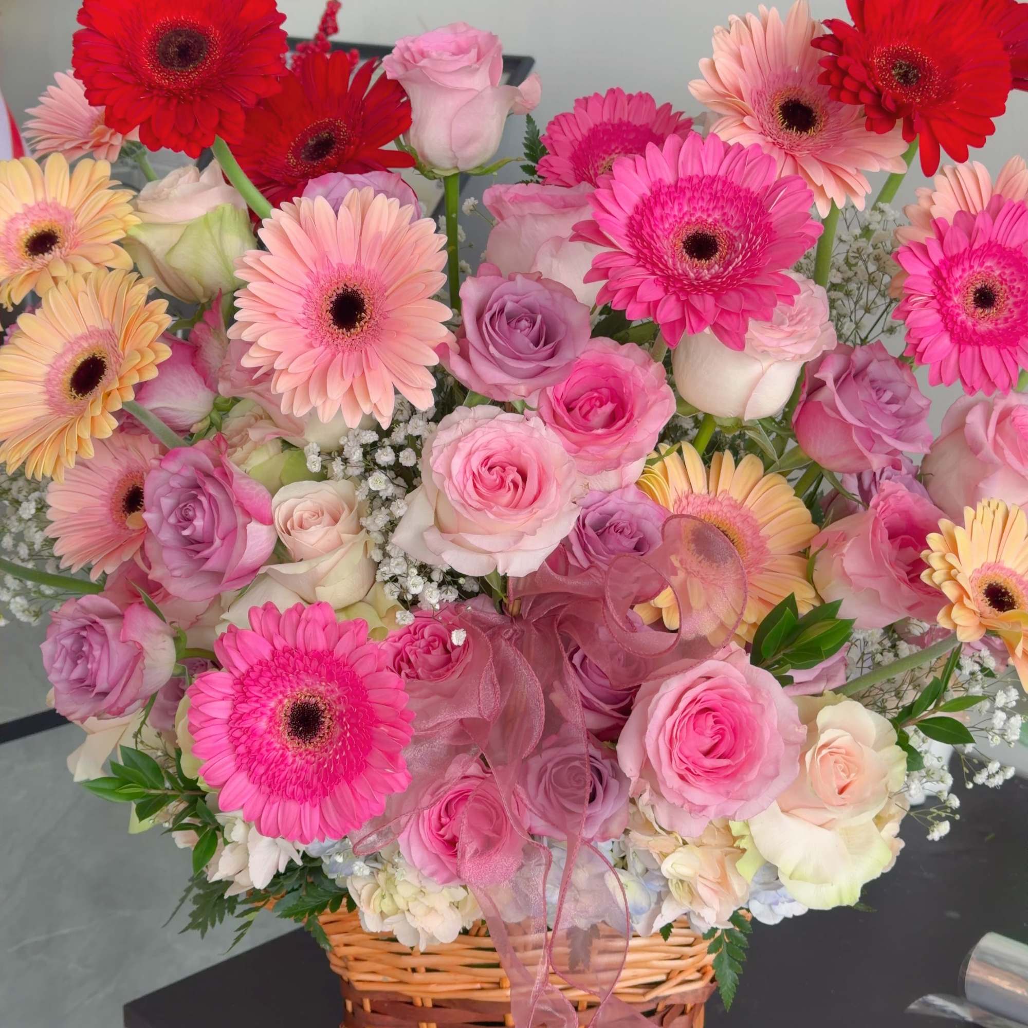The product contains roses, gerbera daisies, green leaves stuffed, and is placed