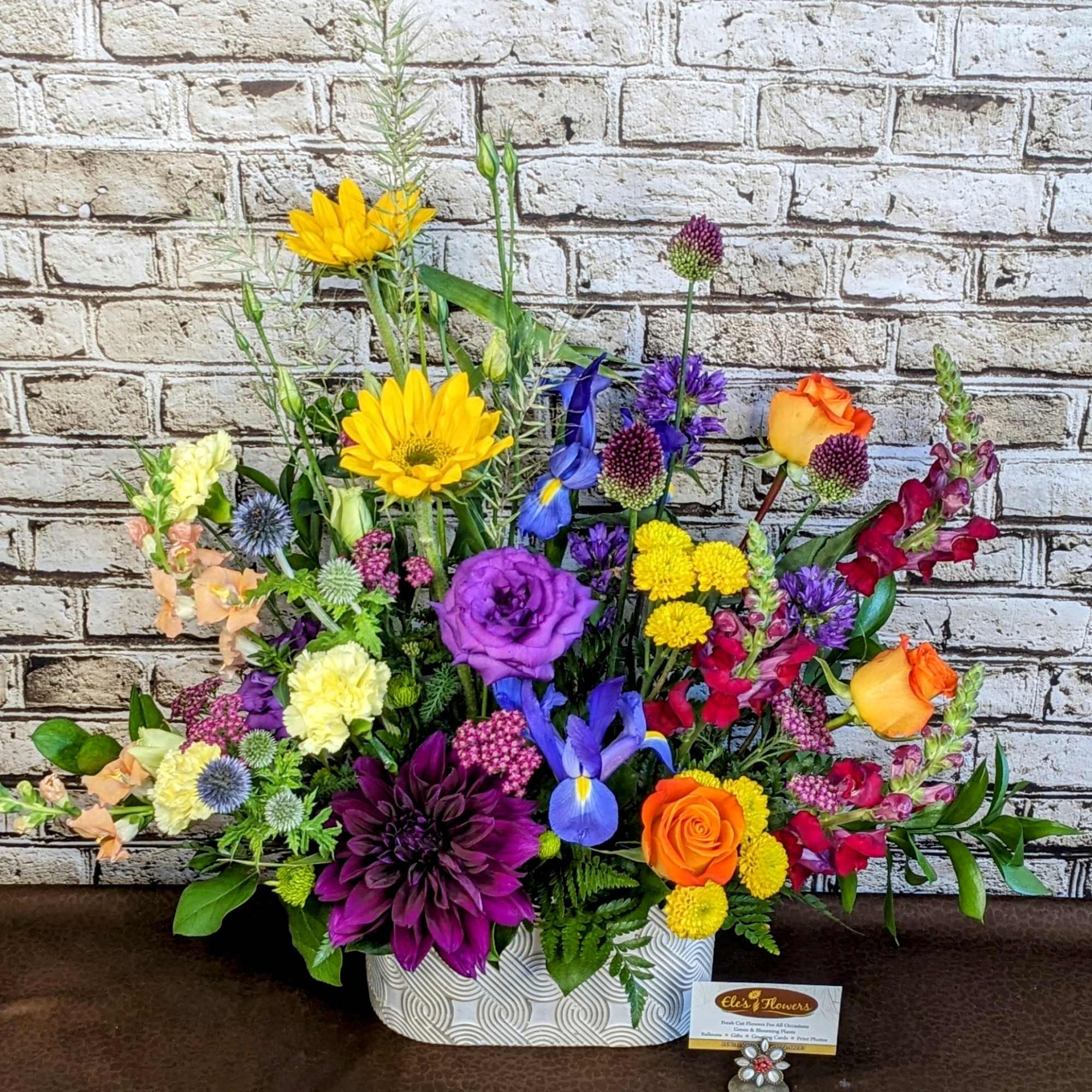 Colorful mixed flower arrangement in a patterned white container
