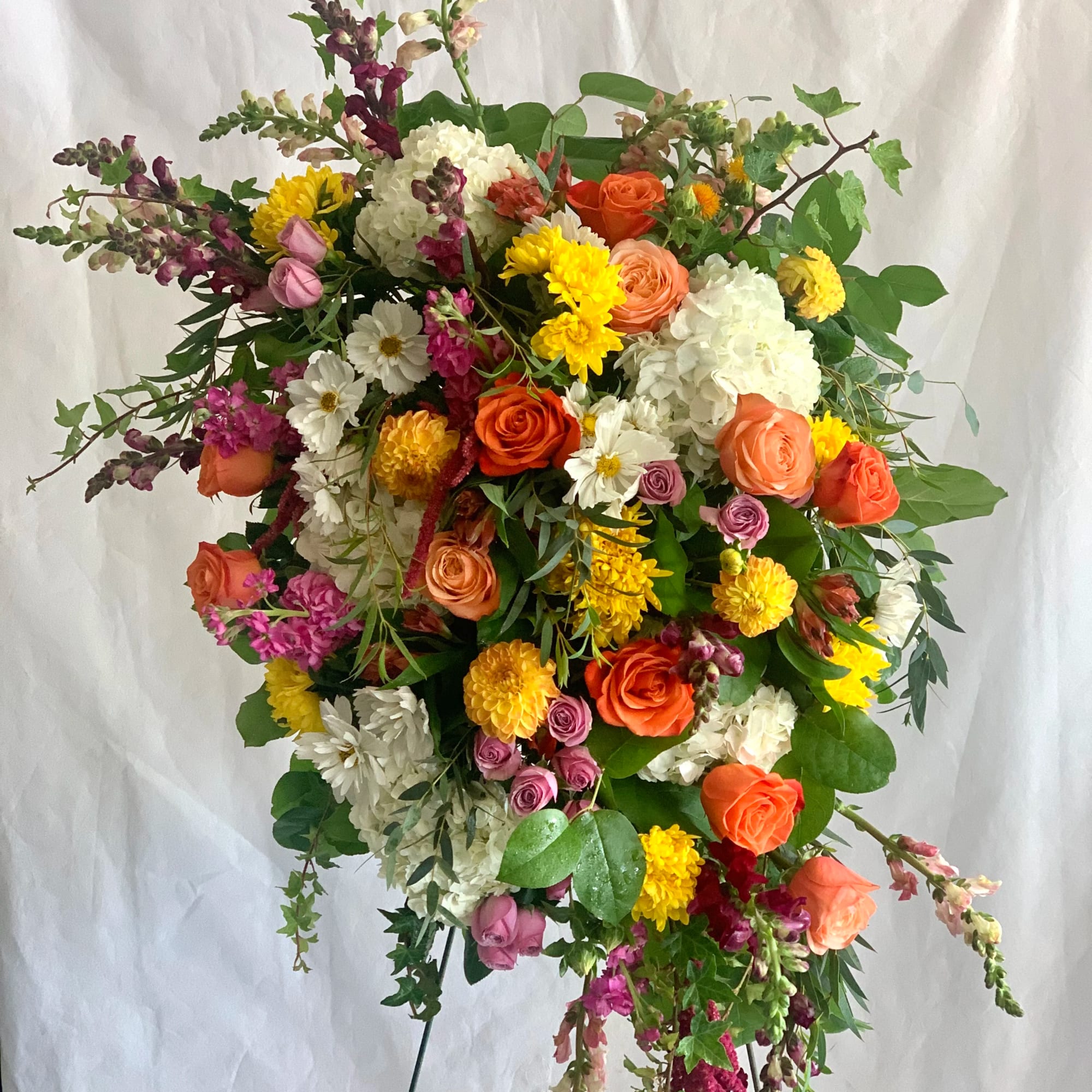 Large mixed floral arrangement with orange, white, yellow, and pink blooms