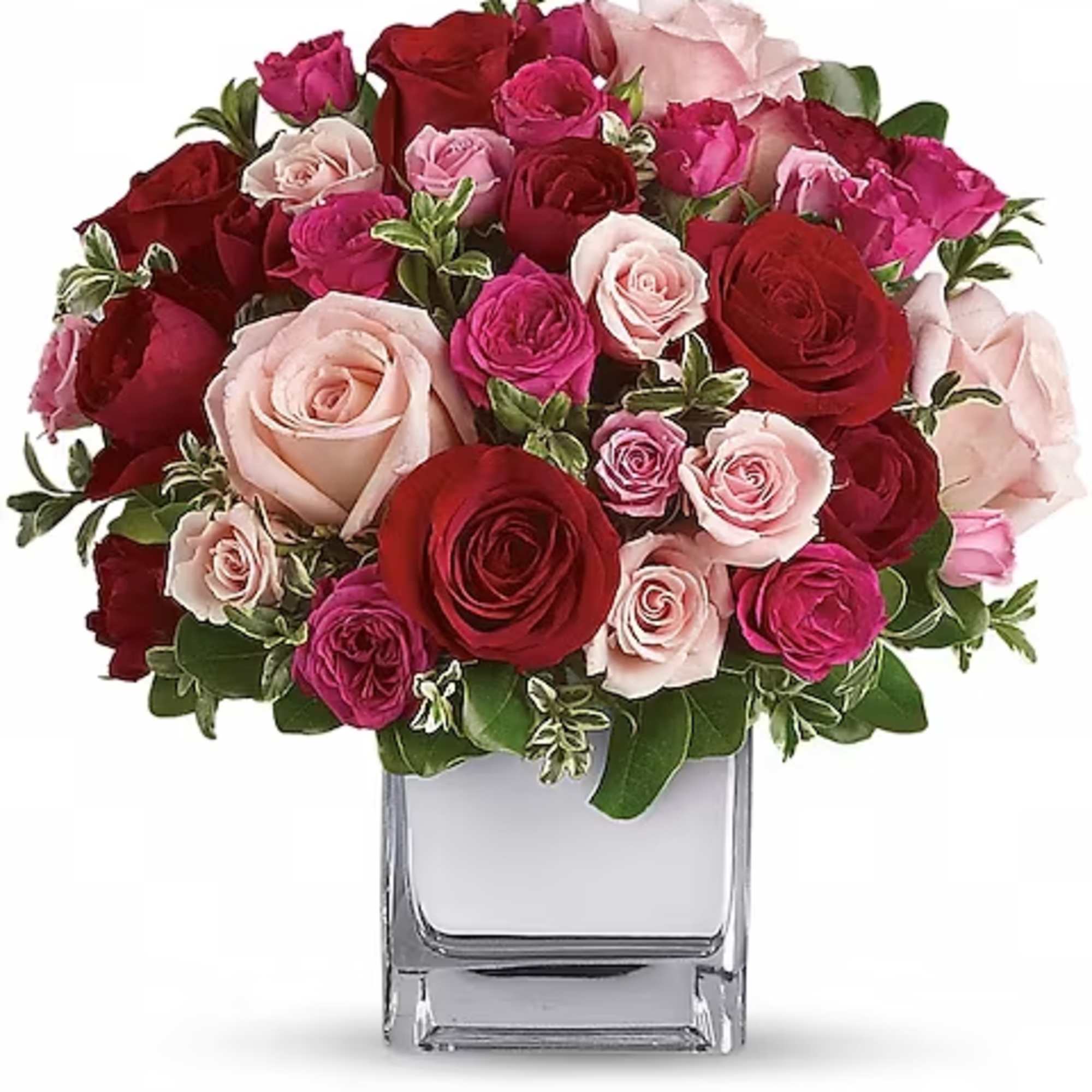 Bouquet of red, pink, and blush roses in a clear square vase