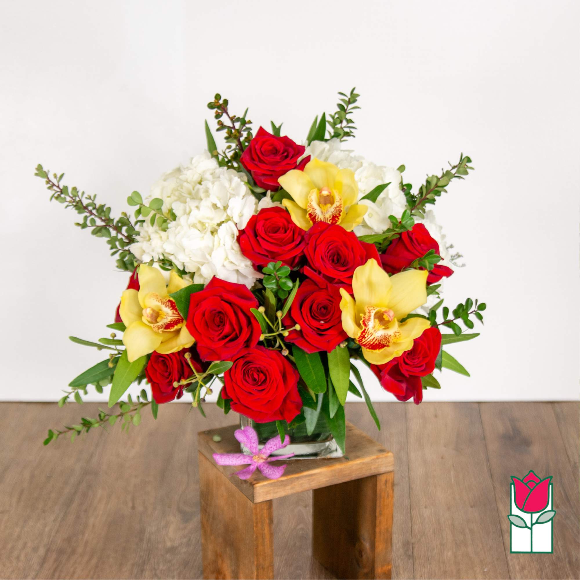 Bouquet of red roses, white hydrangeas, and yellow orchids in a glass vase