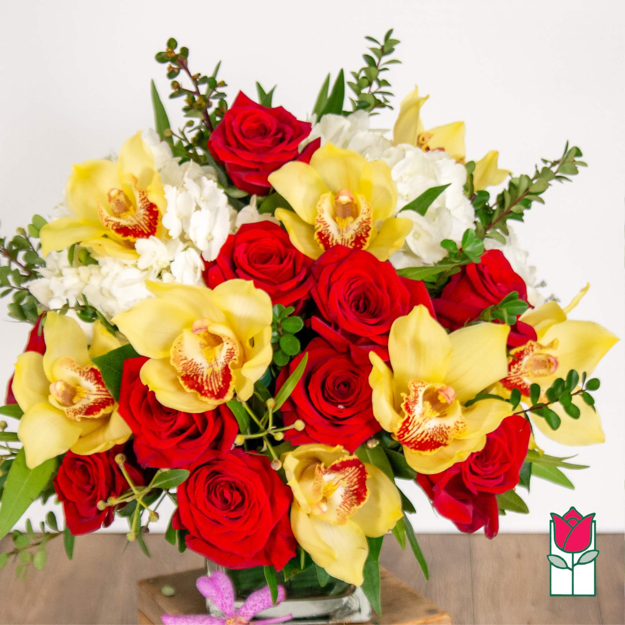 Bouquet of red roses and yellow orchids in a glass vase