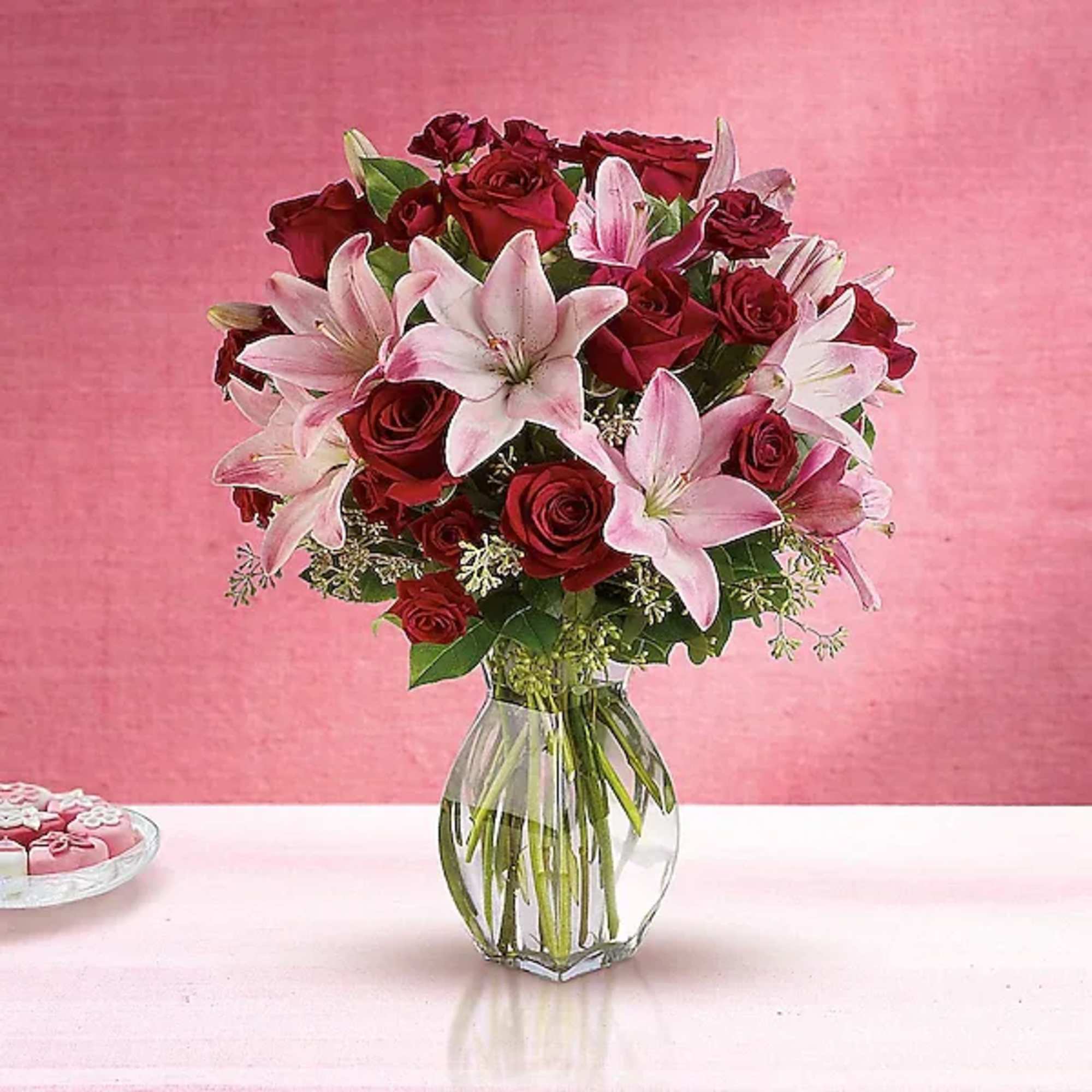 Bouquet of red roses and pink lilies in a clear glass vase
