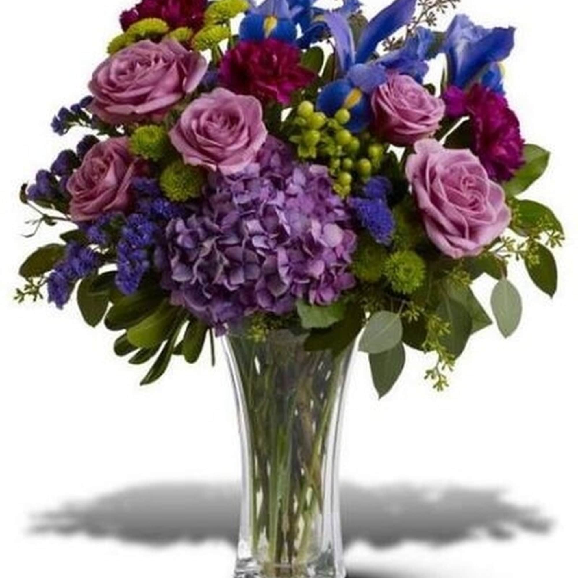 Purple and blue mixed flower arrangement with roses, hydrangea, and irises in a clear glass vase