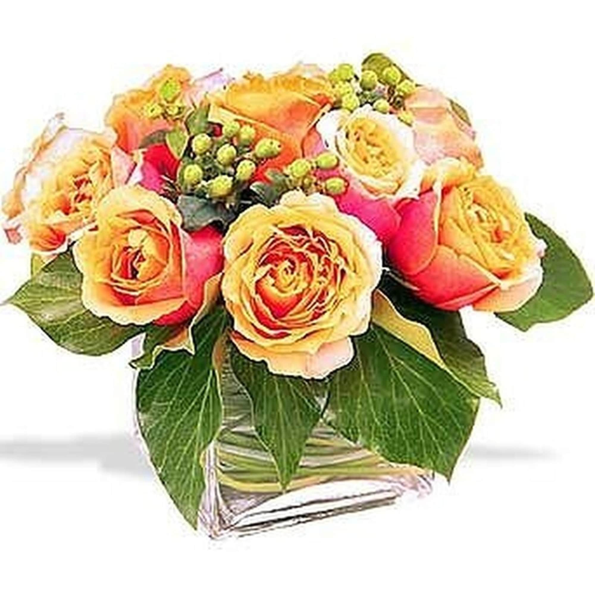Short arrangement of orange and yellow roses with berries in a clear glass cube vase