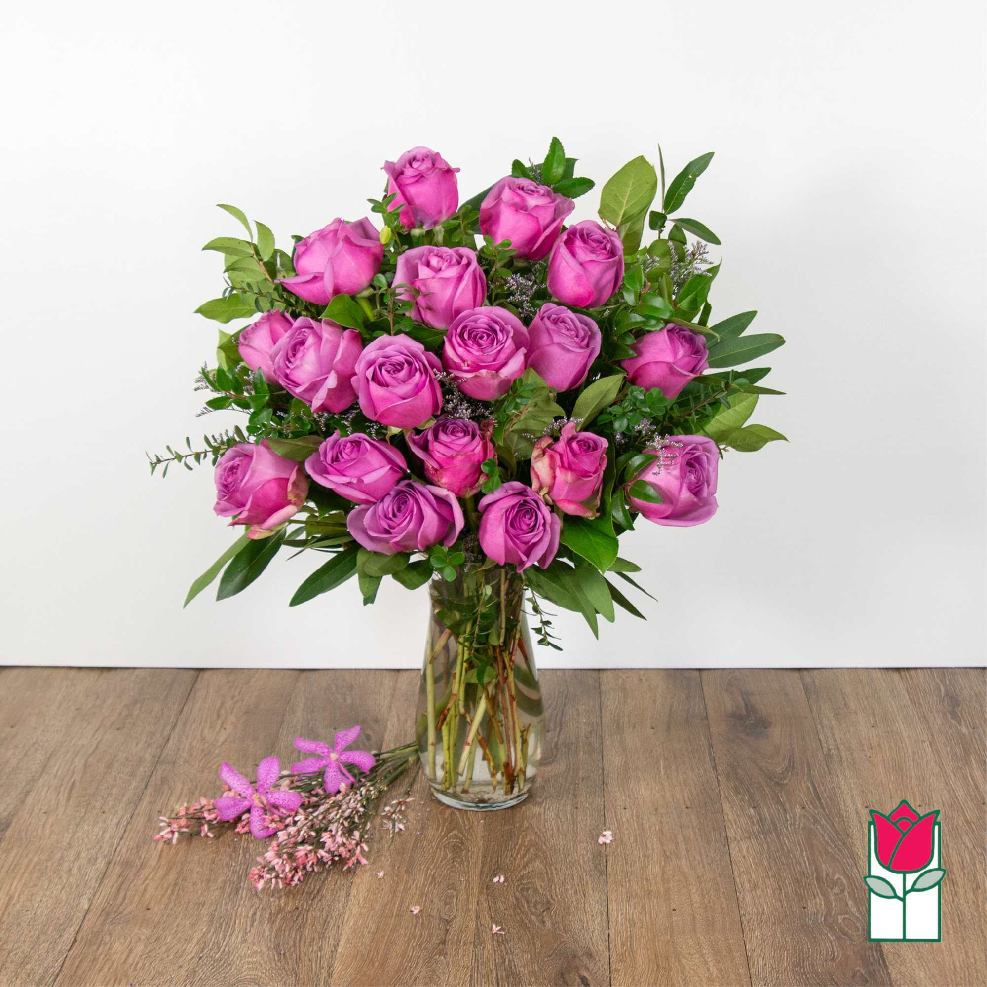Pink roses arranged in a clear glass vase with greenery