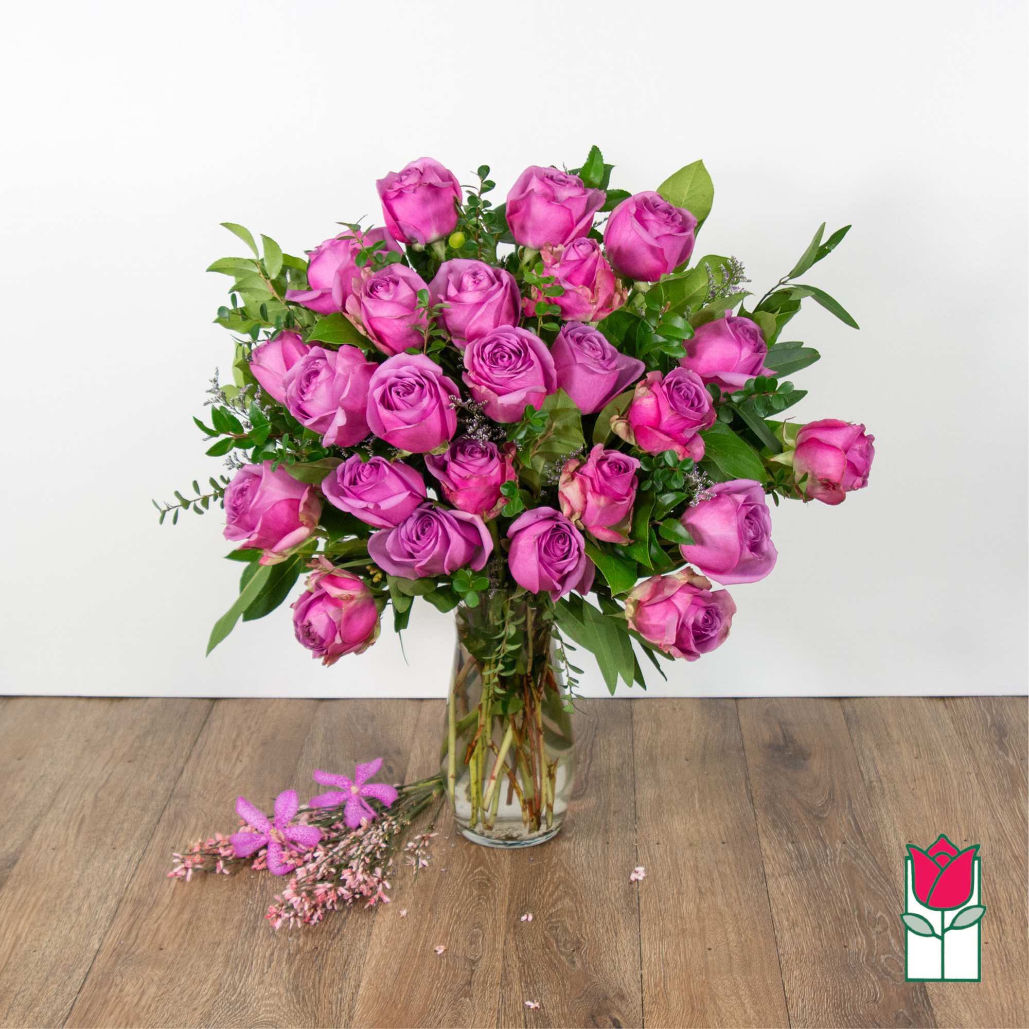 Pink roses arranged in a clear glass vase with greenery