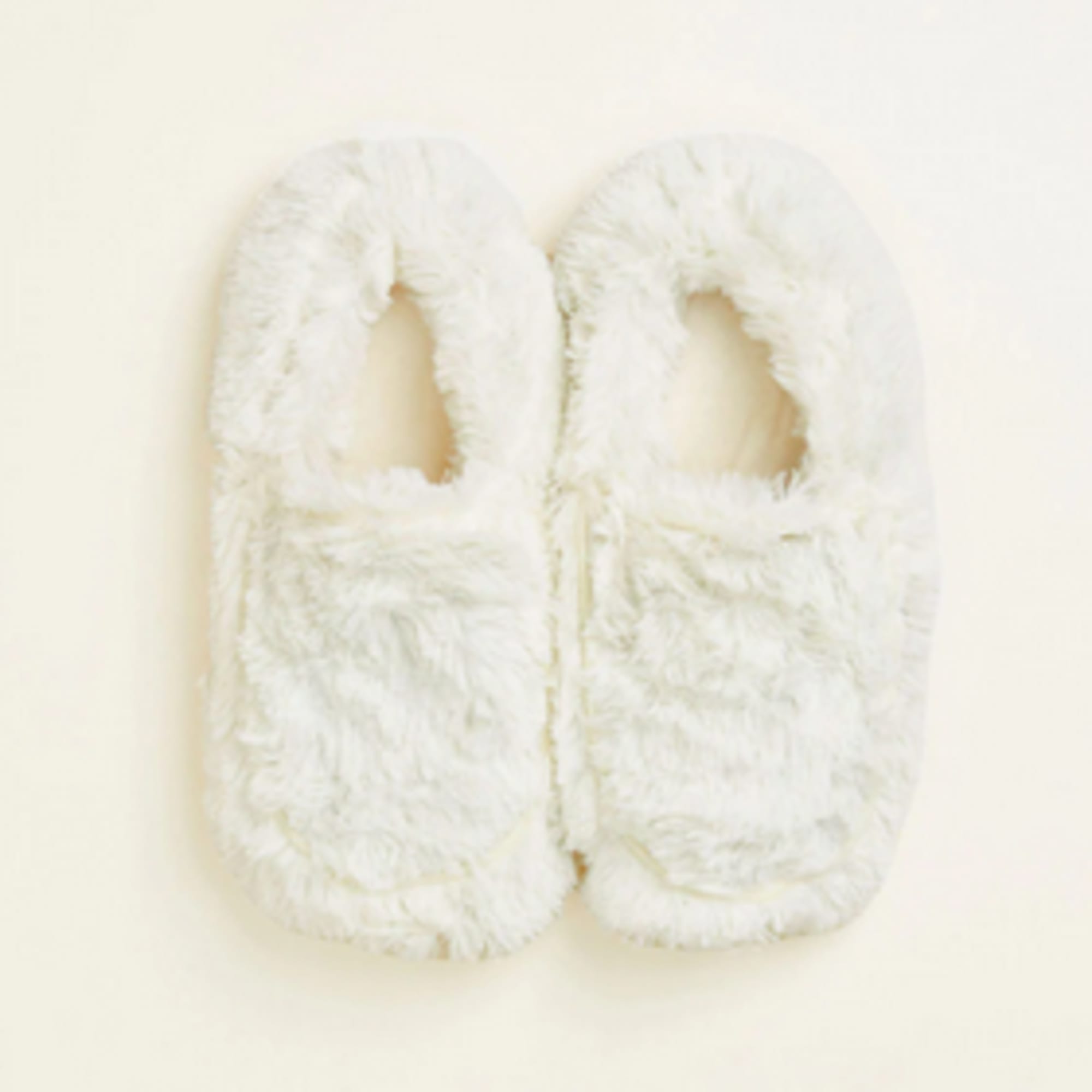 Pair of white fuzzy slippers on a light background