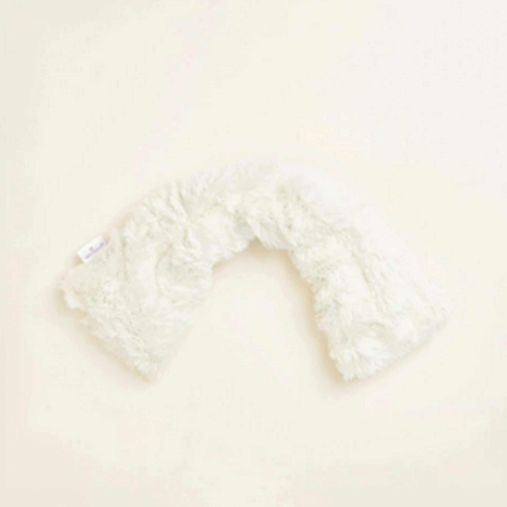 White fluffy U-shaped plush neck pillow on a light background