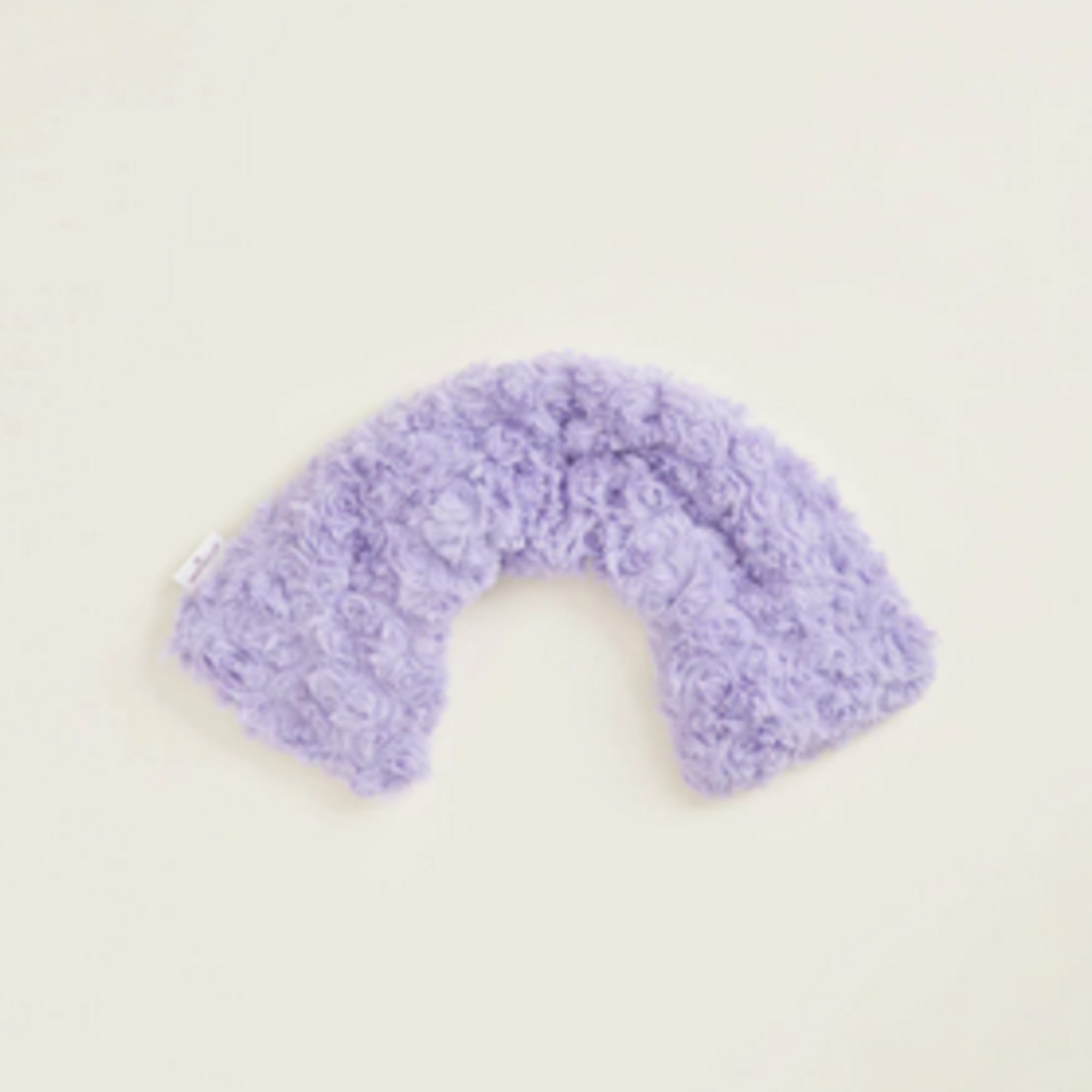 Lavender fuzzy U-shaped neck pillow on a plain background