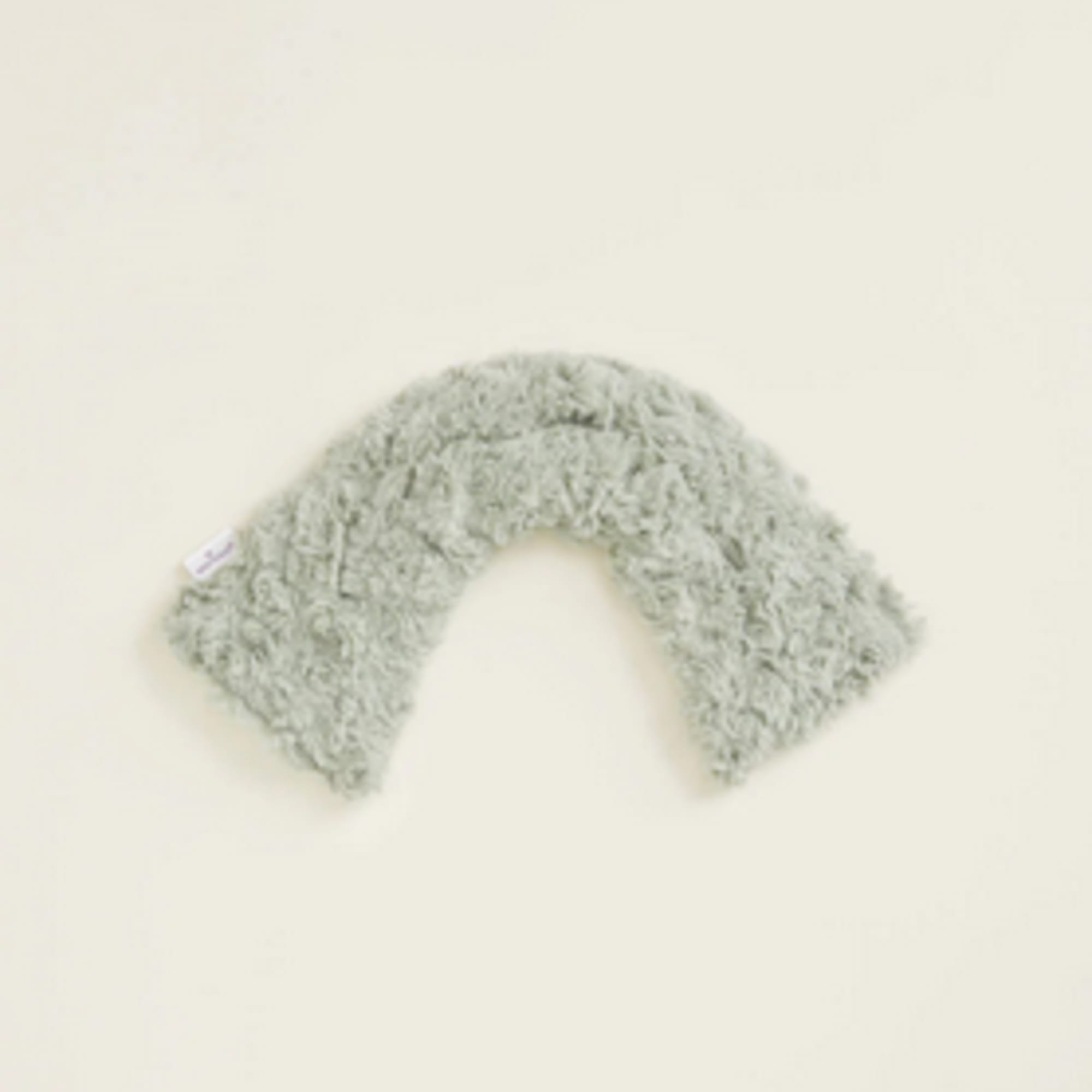 Gray fuzzy U-shaped plush pillow on a plain background