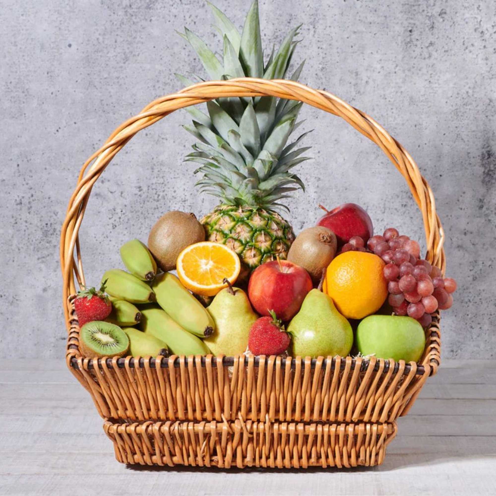 Wicker basket filled with assorted fruit and a pineapple centerpiece