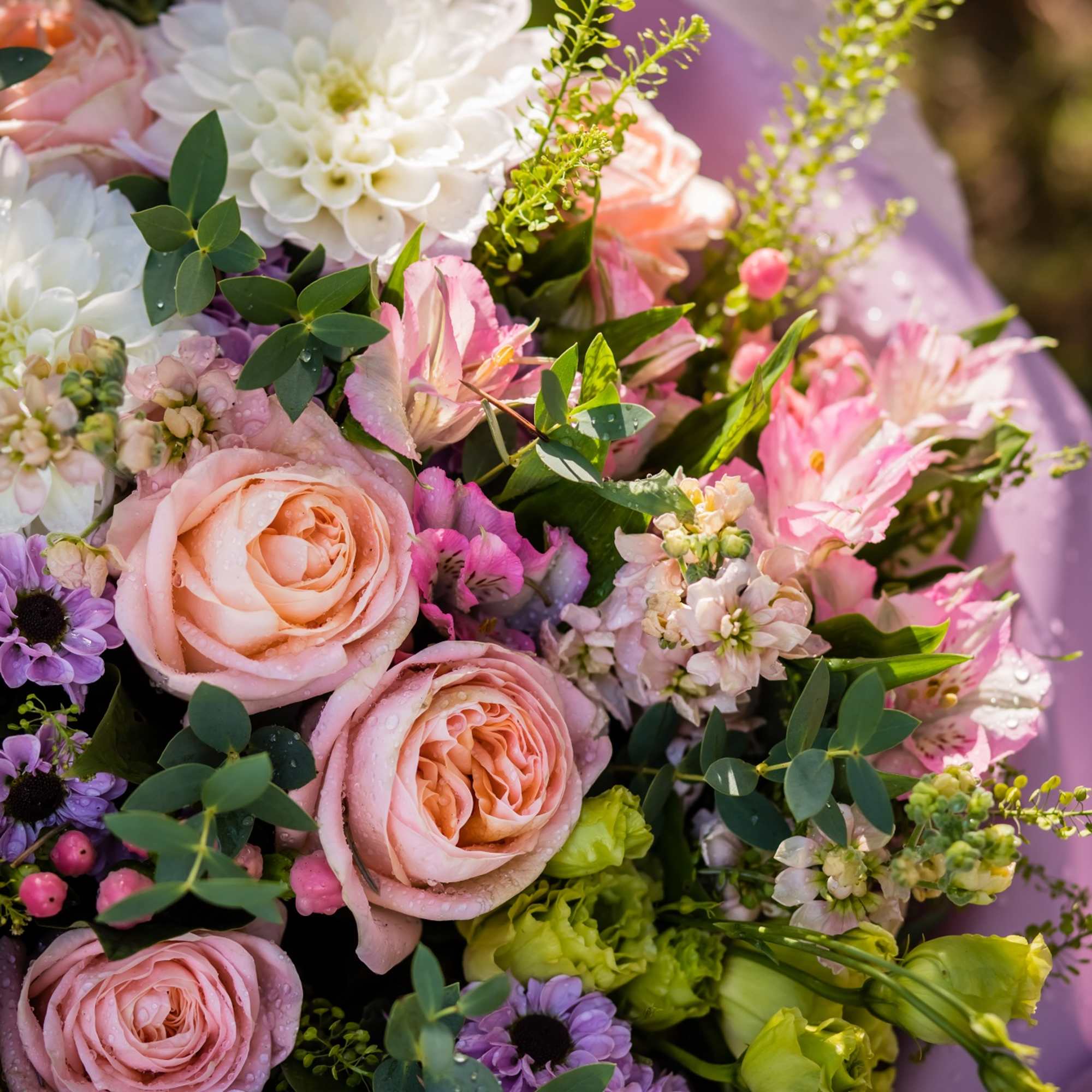 Wedding bouquet with pink roses, white blooms, and purple flowers