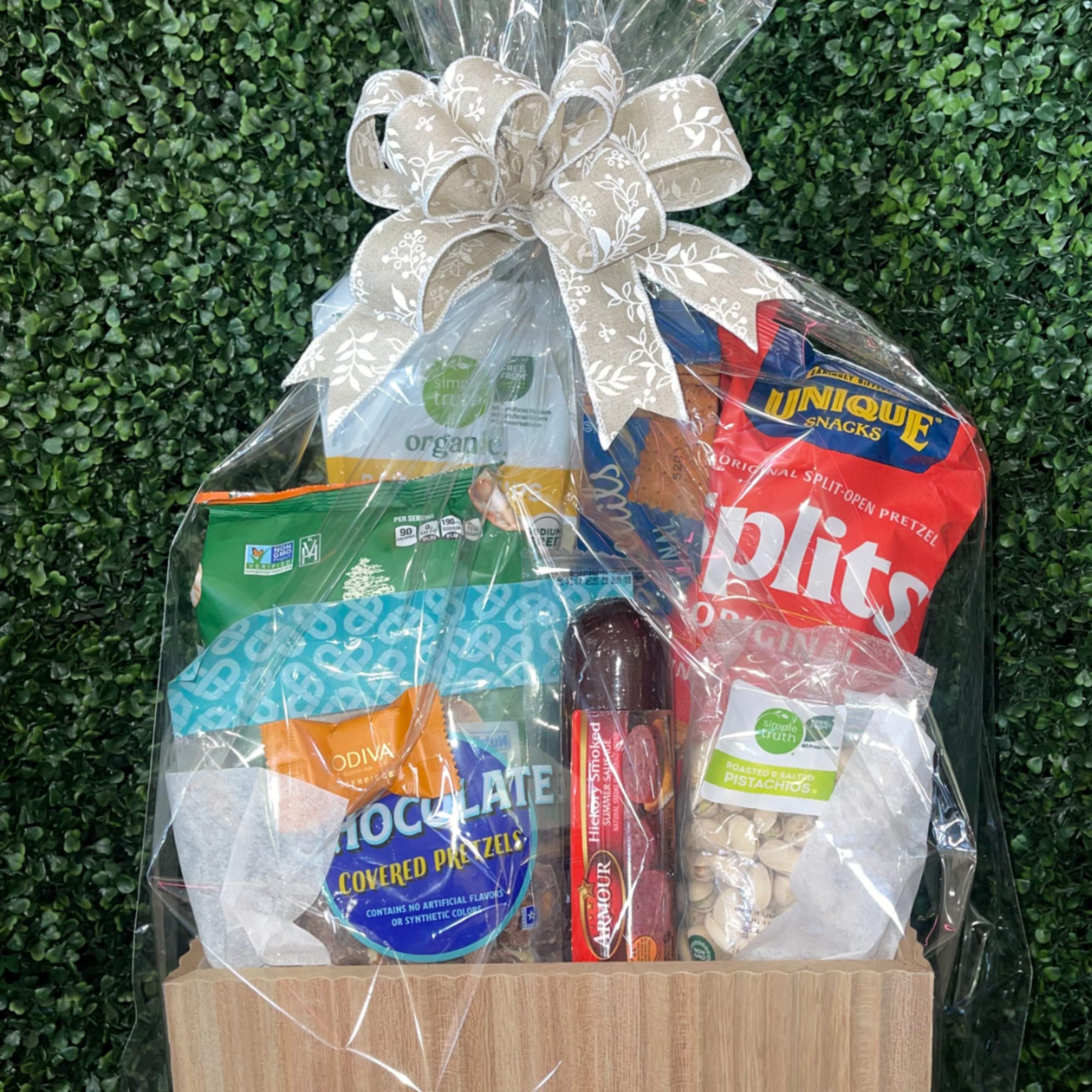 Snack gift basket wrapped in cellophane with a large patterned bow on top