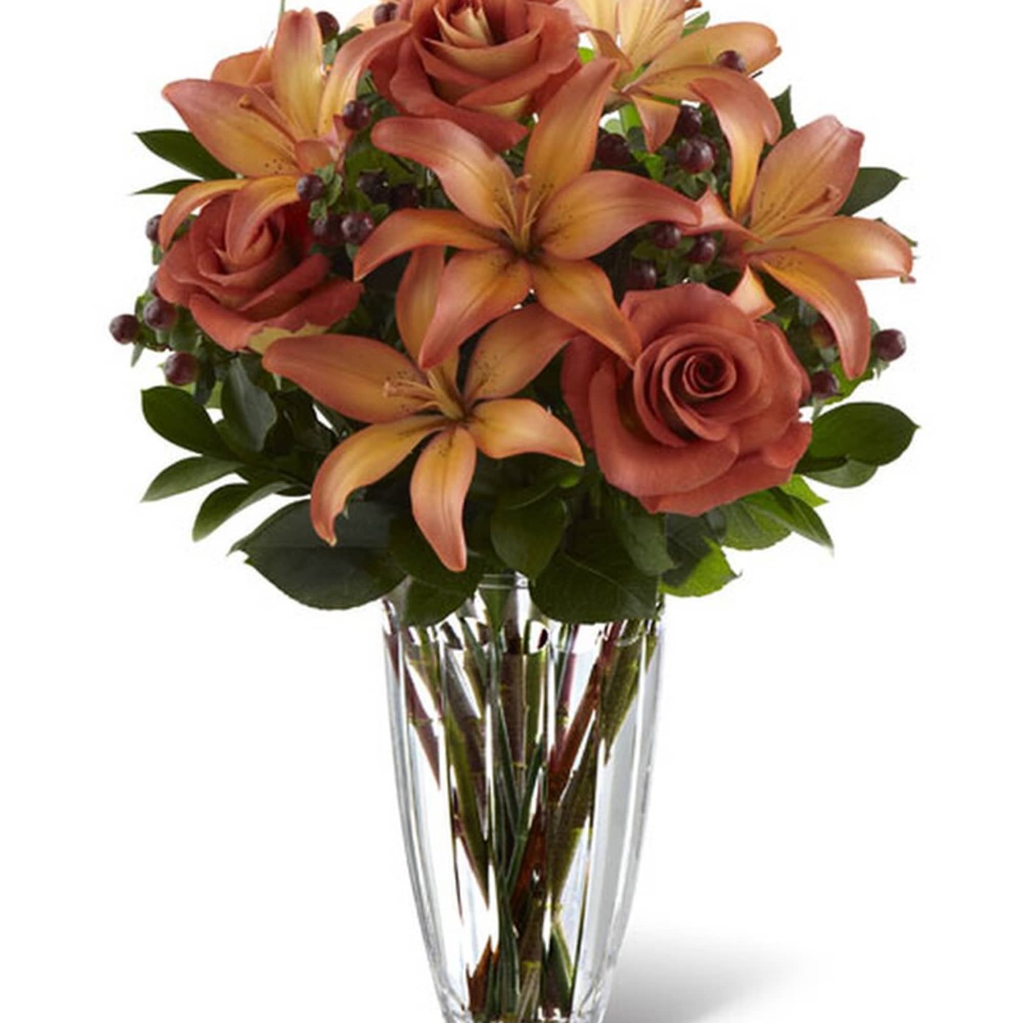 Clear vase with orange roses and lilies arranged in a compact bouquet