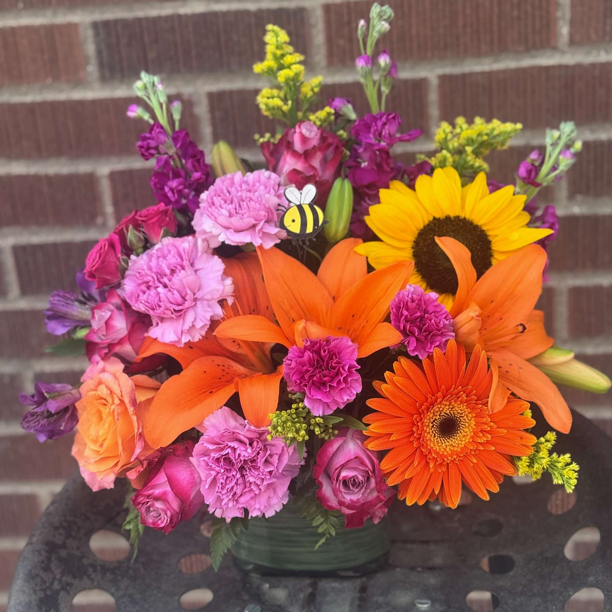 Bright mixed bouquet with sunflowers, orange lilies, and pink roses in a vase