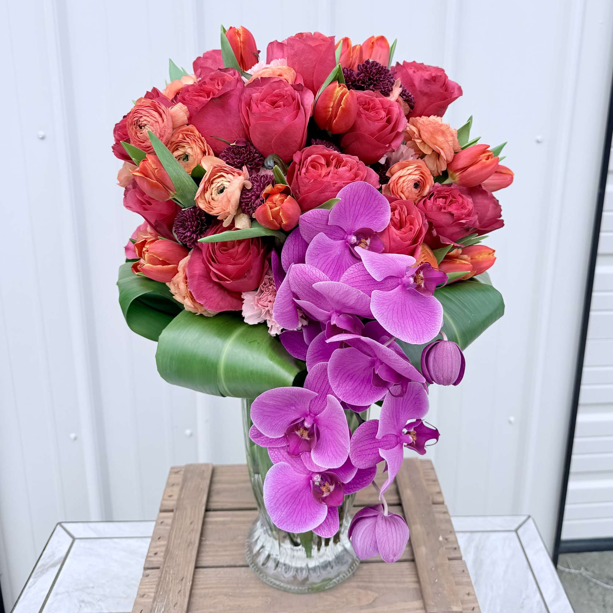 A bold cascade of vivid purple Phalaenopsis and dendrobium orchids drapes over