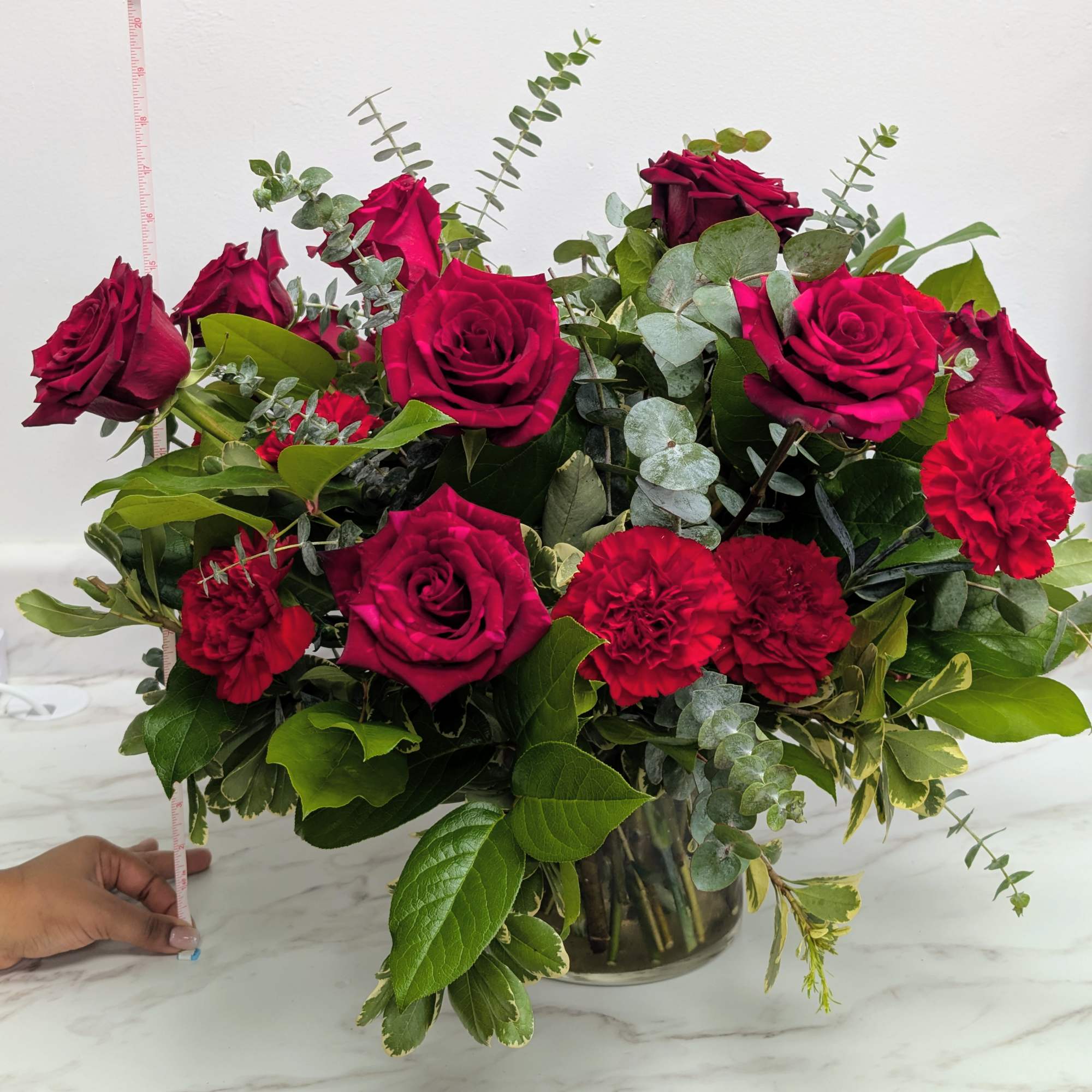 Red roses and carnations in a glass vase with eucalyptus